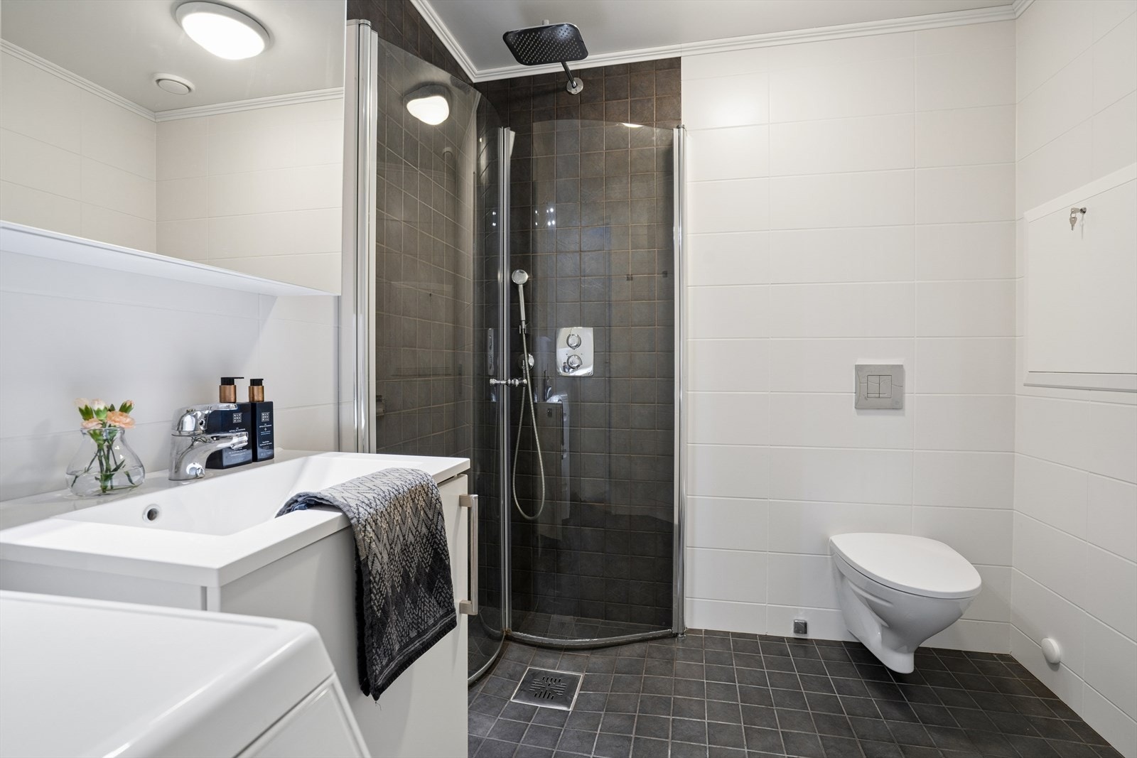 Badet er utført med flislagte overflater og har elektriske varmekabler - Her finner du dusjhjørne m/innfellbare glassdører, vegghengt toalett, baderomsinnredning og opplegg for vaskemaskin Galleribilde