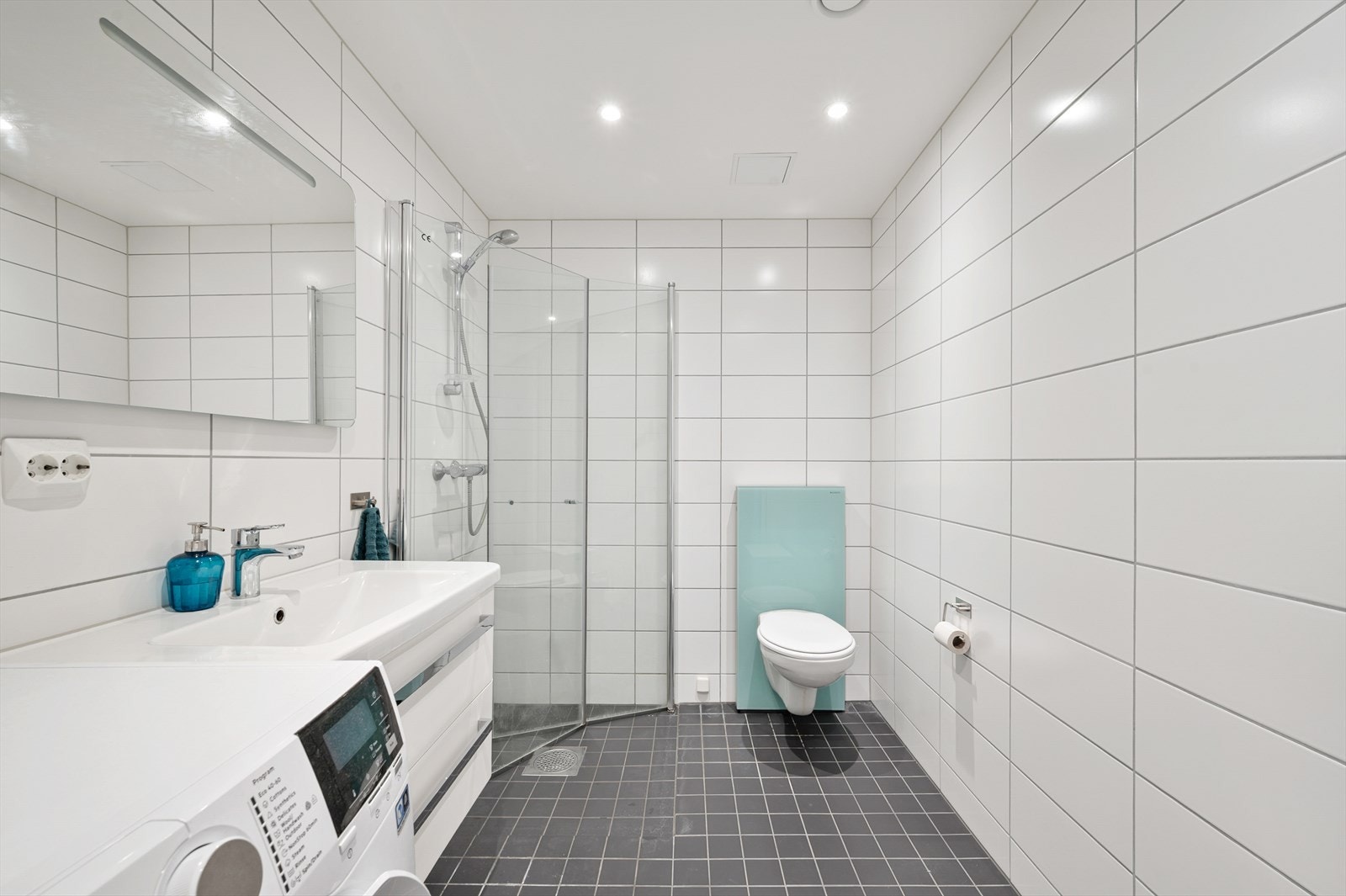 Badet er utstyrt med servantinnredning med skuffer, toalett og opplegg for vaskemaskin Galleribilde