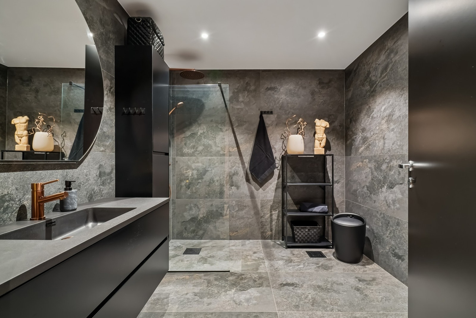 Badet i 1.etasje er innbydende og moderne. Store fliser på vegger og gulv med vannbåren gulvvarme, hvit himling med ledspotter og dimming. Galleribilde