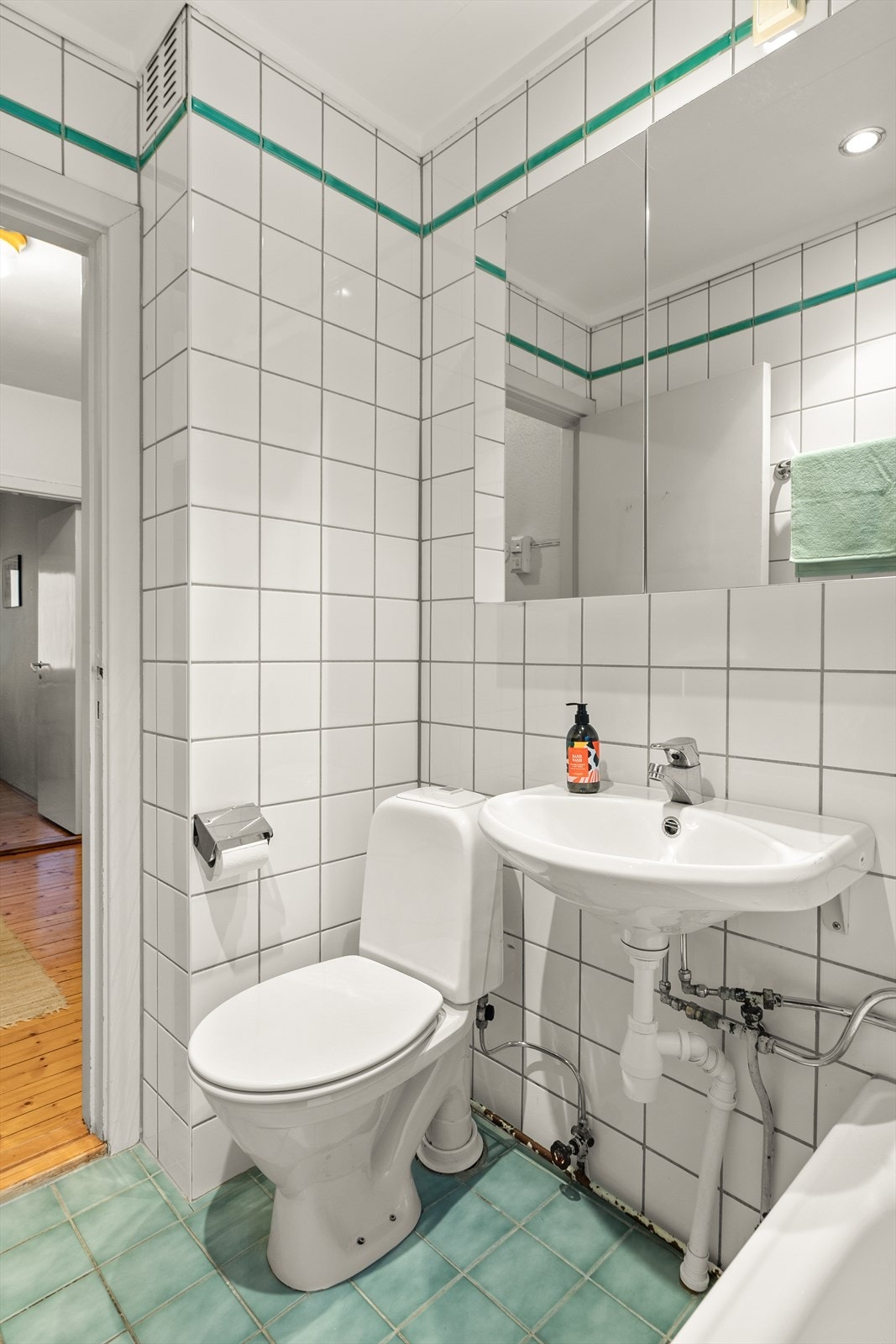 Videre er badet innredet med gulvstående klosett, servant, speilskap og badekar. Galleribilde