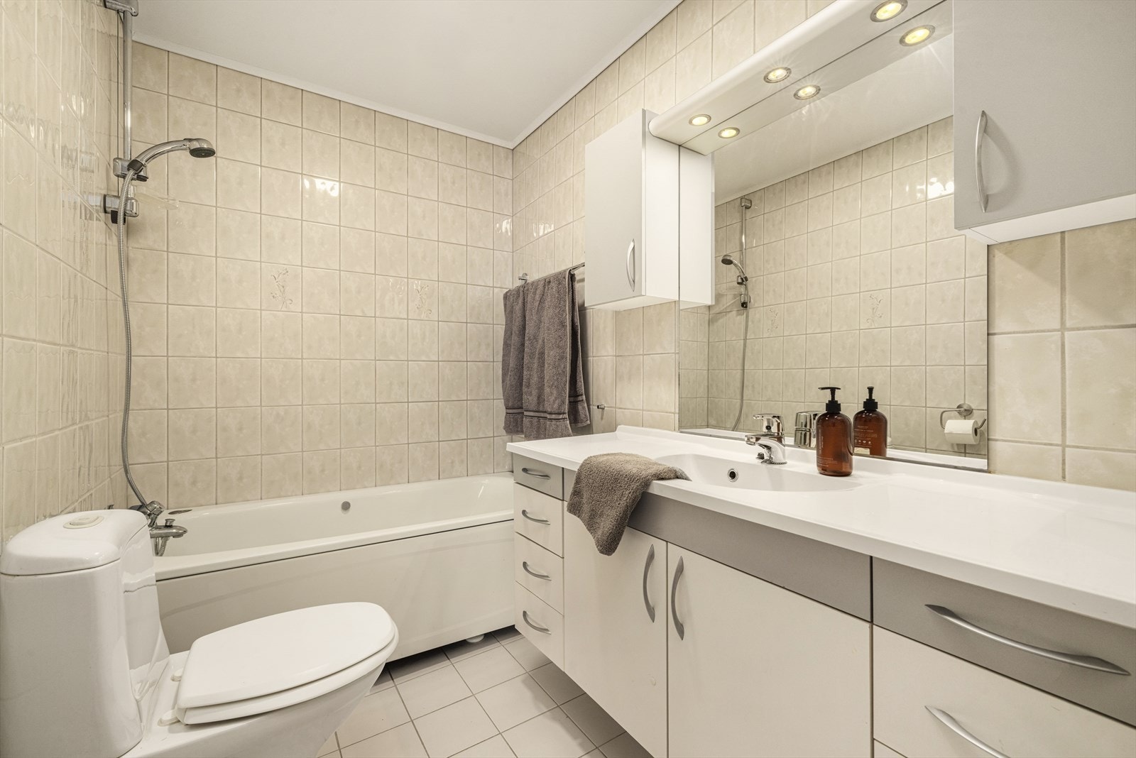 Baderom 2 i soveromsfløyen har lyse fliser på vegger og gulv, med varmekabler Galleribilde