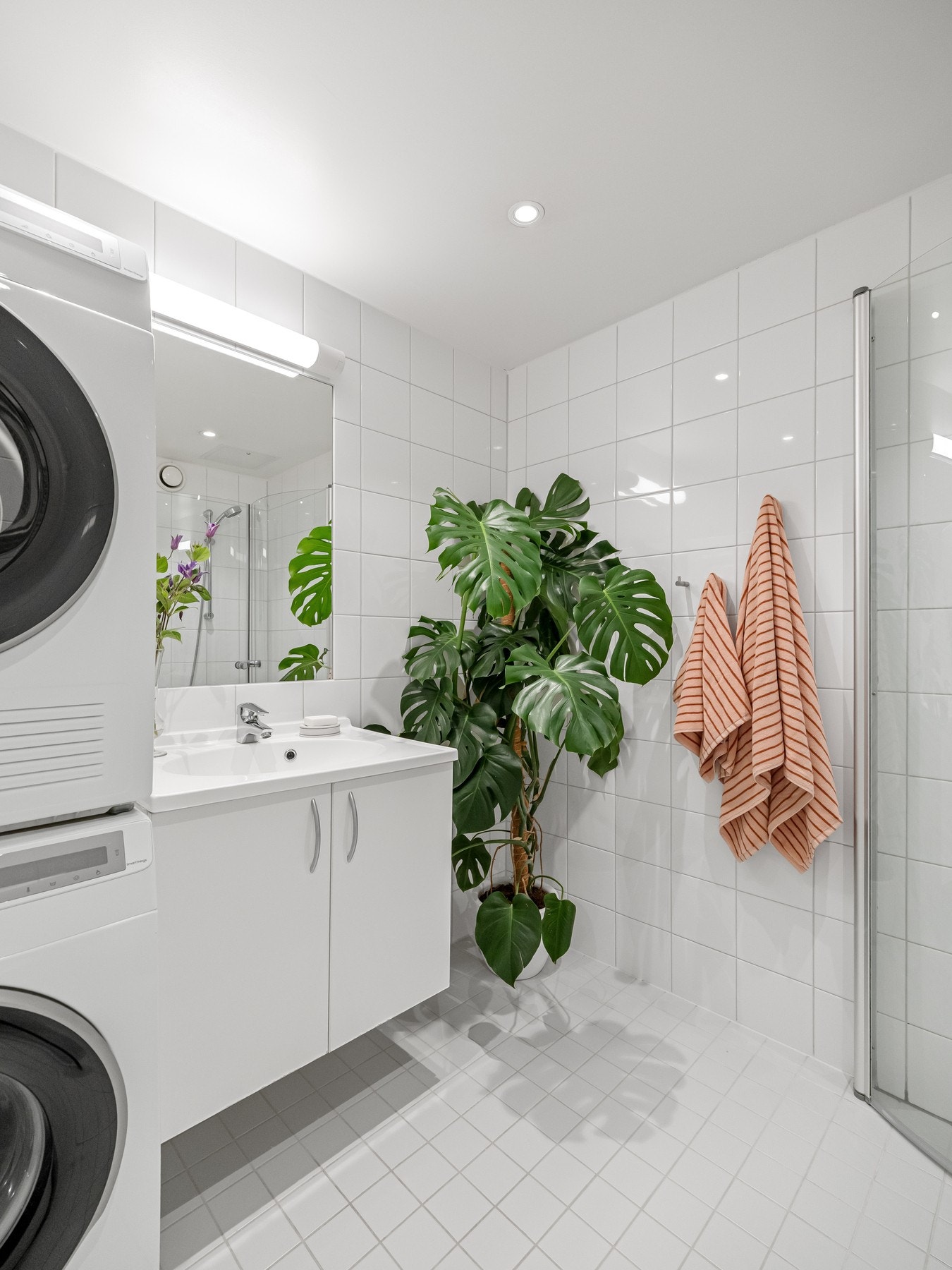 Badet er innredet med toalett, servant med underskap, dusj med innfellbare glassdører og speil på vegg med belysning over. Galleribilde