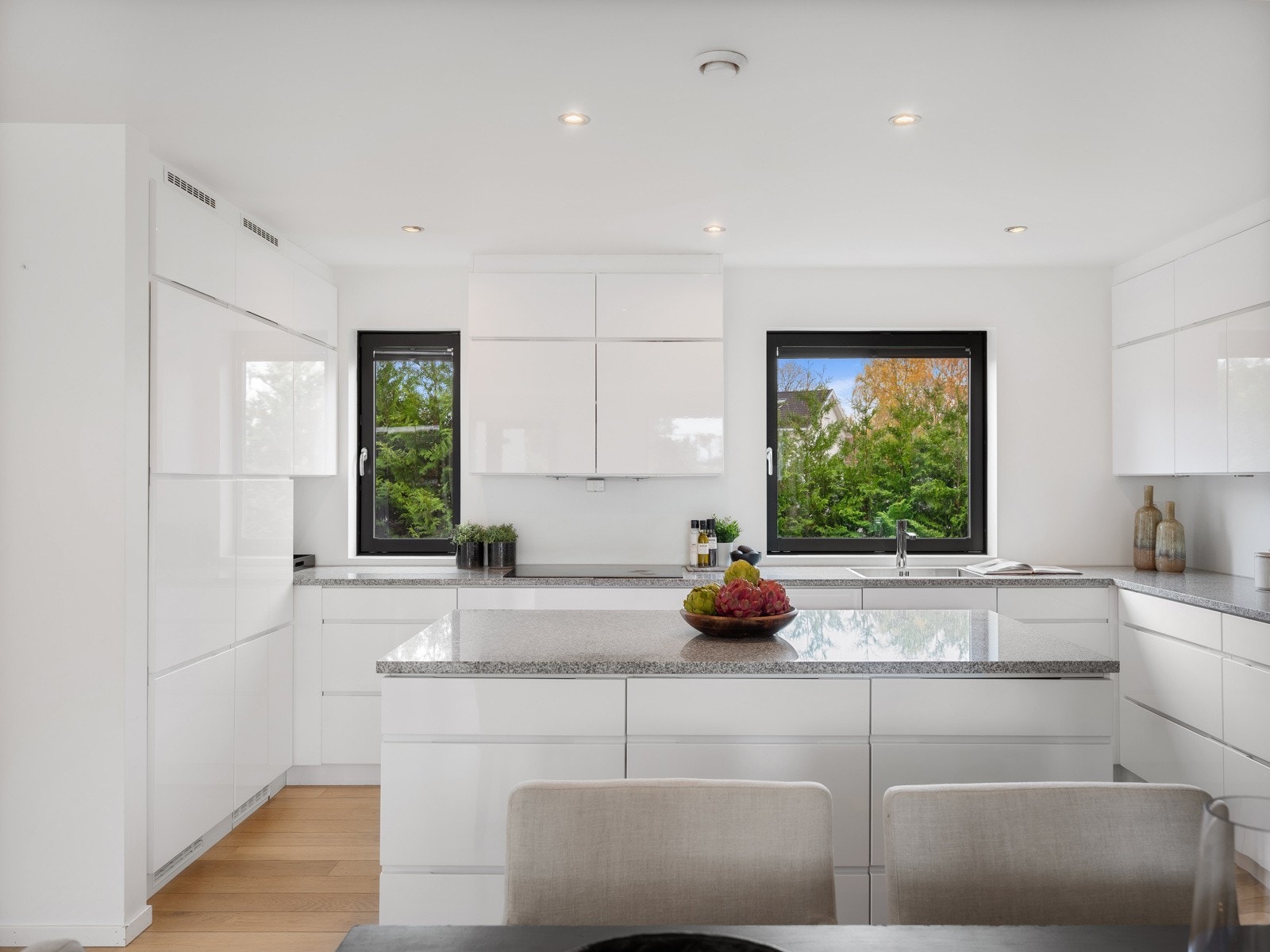 Kjøkkenet har et tidløst uttrykk med hvite høyglansfronter med integrert gripelist og benkeplater i granitt. Galleribilde