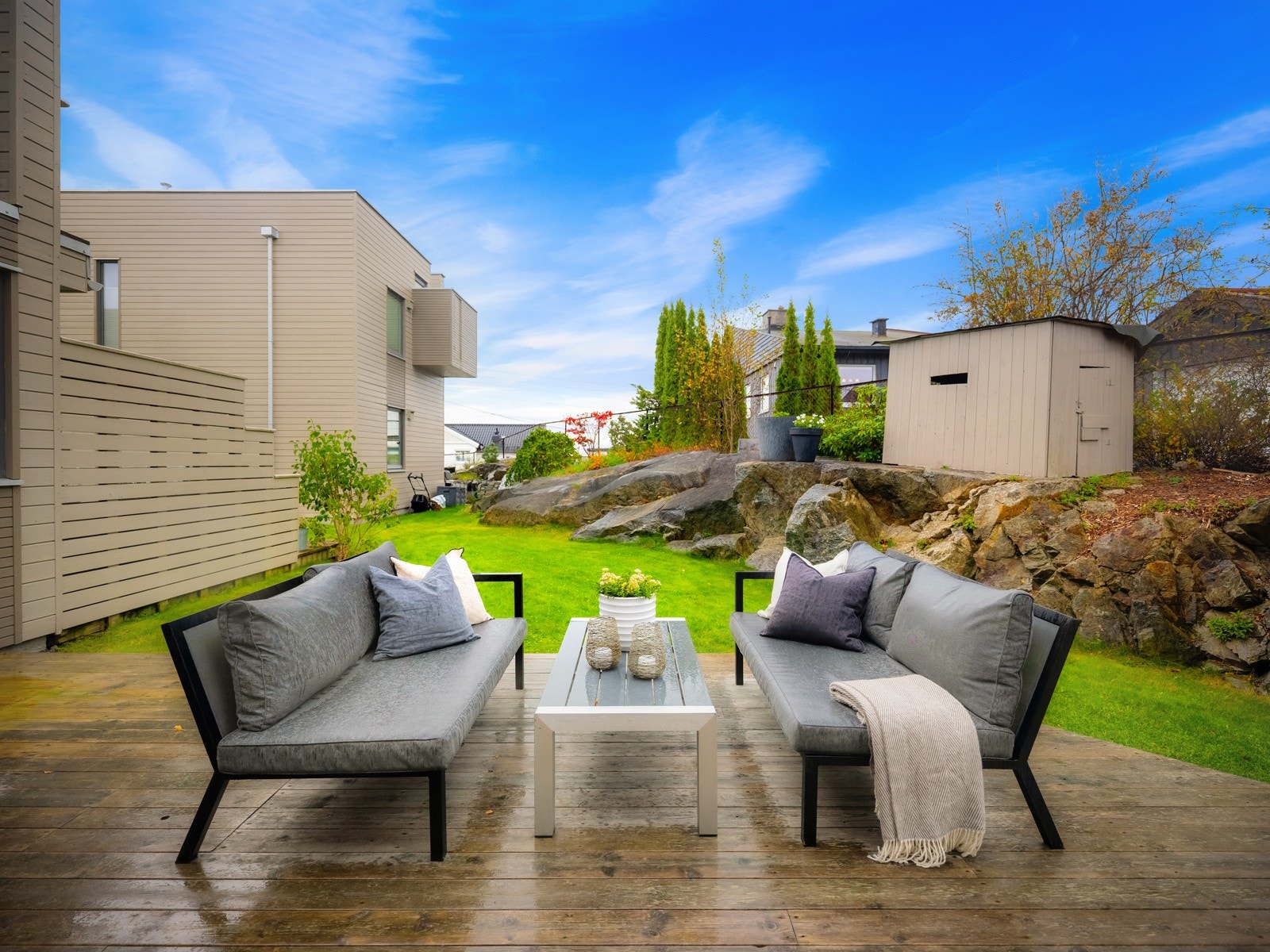 Fra terrassen er det direkte adkomst til hagen med gressplen, naturstein og beplantning i krukker. Galleribilde