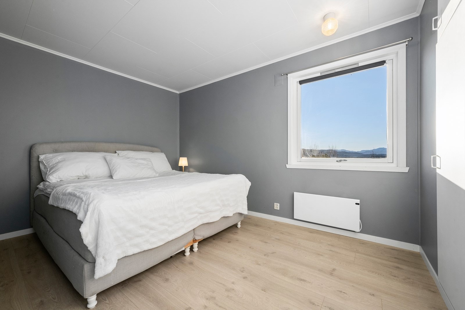 Soverom 2: Romslig hovedsoverom som byr på flott utsikt. Rom er utstyrt med panelovn og integrert garderobeskap. Eier har oppgradert med nytt laminatgulv og gipsplater på vegg. Galleribilde