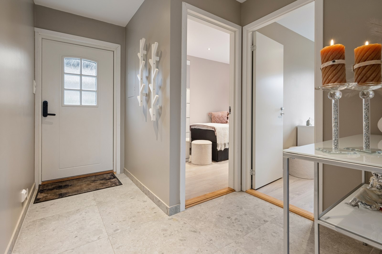 Man ønskes velkommen inn i en romslig gang som er praktisk og pent innredet med store, grå fliser på gulvet. Her har man god plass til å henge fra seg yttertøy og sko. Galleribilde