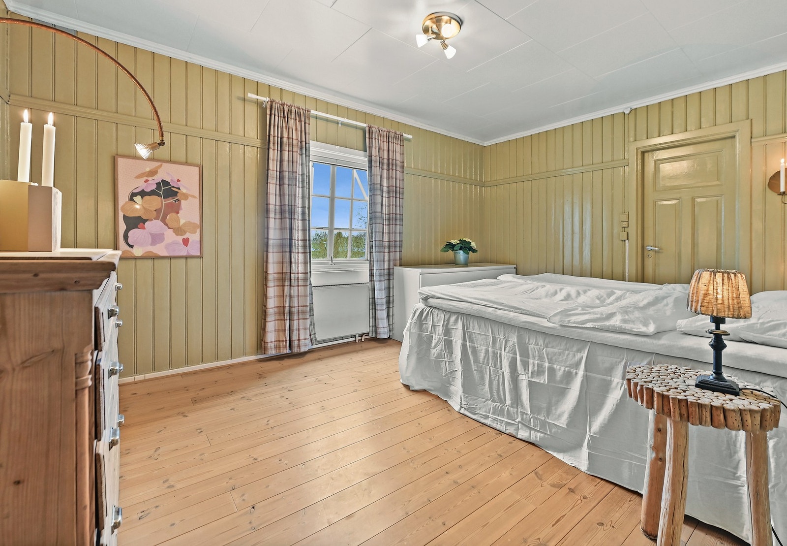 Rom med panelte vegger og tregulv, vindu med utsikt, og enkel belysning i taket. Galleribilde