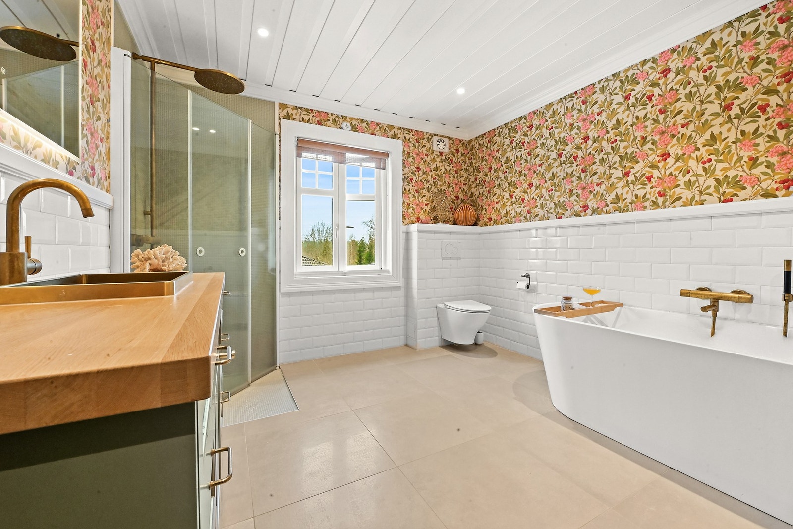 Badet har moderne detaljer med dusj, badekar, og et stort vindu som gir naturlig lys. Galleribilde