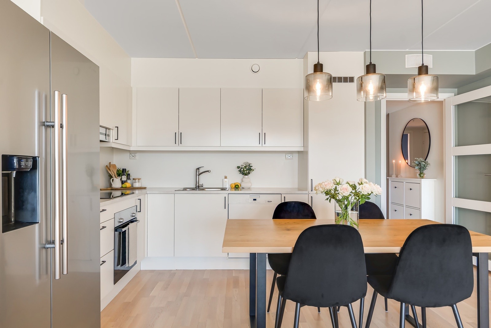 Moderne kjøkken fra HTH med lyse, glatte fronter og laminat benkeplate med nedfelt vaskekum. Kjøkkenet har integrert oppvaskmaskin, induksjonstopp og stekeovn, samt ventilator over kokeplass. Det er også montert vannstoppsystem og komfyrvakt. Galleribilde