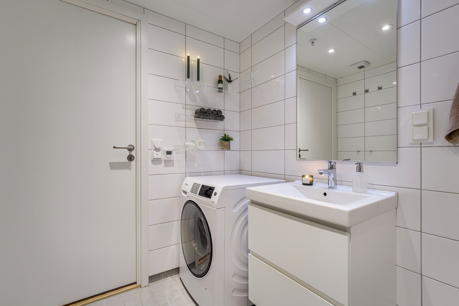 Opplegg for vaskemaskin. Baderommet har fliser på gulv og vegger, vannbåren gulvvarme, balansert ventilasjon, samt himling med lakkerte stålplater og innfelte downlights. Galleribilde