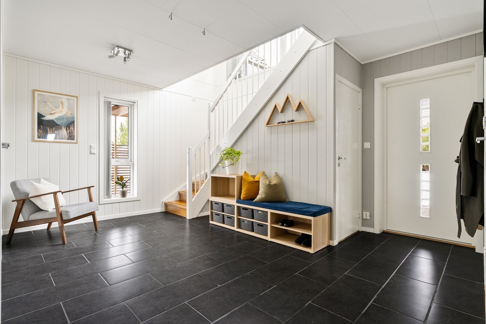 Hallen er flislagt med varme i gulvet. Under trapperommet er det også godt med lagringsrom. Galleribilde