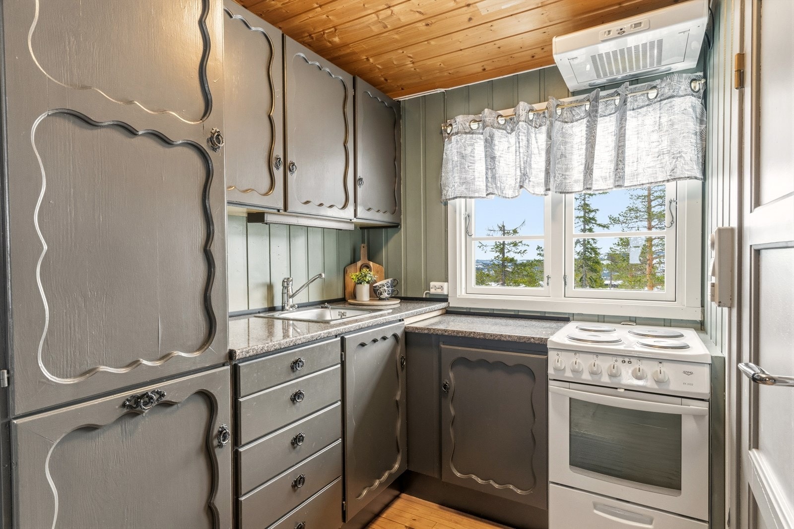 Kjøkkeninnredningen har profilerte fronter i mørkegrønn farge som skaper en fin sammenheng med de naturskjønne omgivelsene. Galleribilde