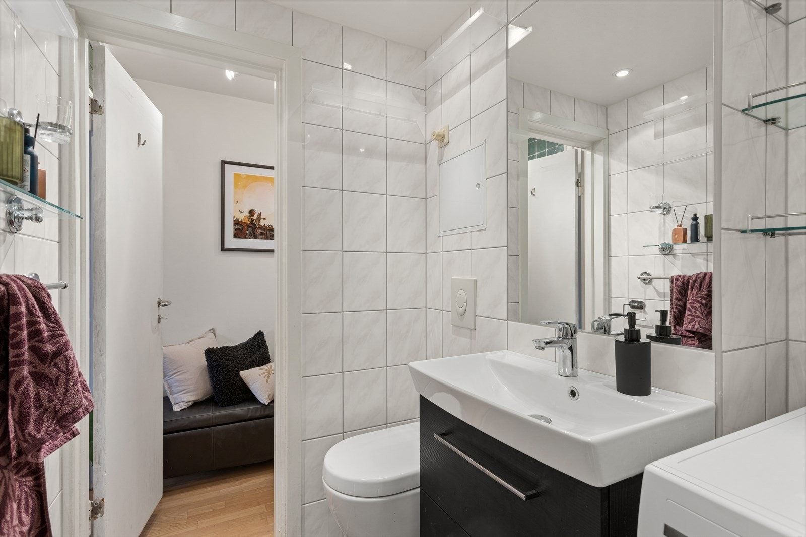 Speil, vegghengt toalett og dusj i hjørnet bak svingbare glassvegger - opplegg for vaskemaskin Galleribilde