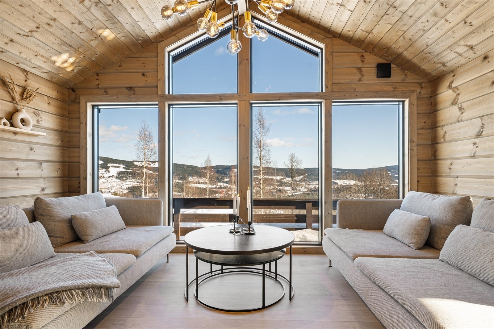 Fra stuen åpner det karakteristiske utstikket seg mot naturen og skaper en flott utsiktssone hvor store glassflater slipper landskapet helt inn i rommet. Her bader stuen i naturlig lys, samtidig som du kan nyte den rolige utsikten mot skog og åsrygger. Galleribilde