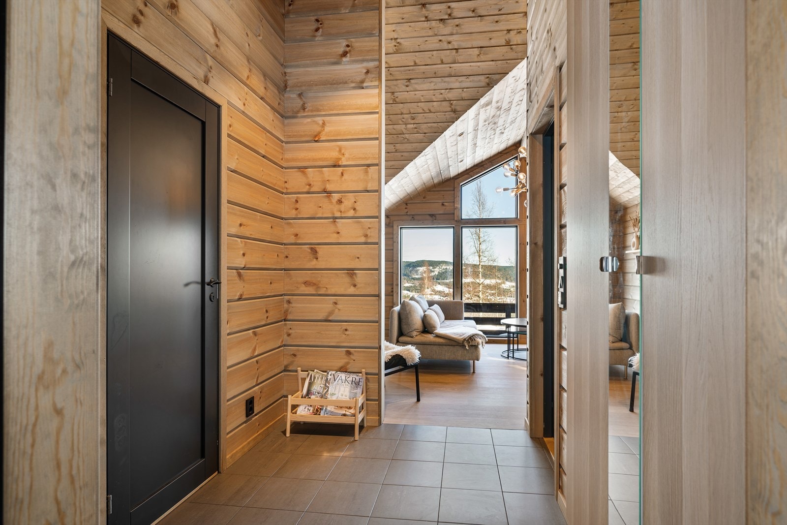 Velkommen inn! Entréen ønsker deg velkommen med en stilren og lun atmosfære - her møtes moderne fjellhyttepreg og praktiske løsninger. Gulvet er belagt med mørke fliser med behagelig gulvvarme, perfekt etter en dag ute i frisk fjelluft. Galleribilde