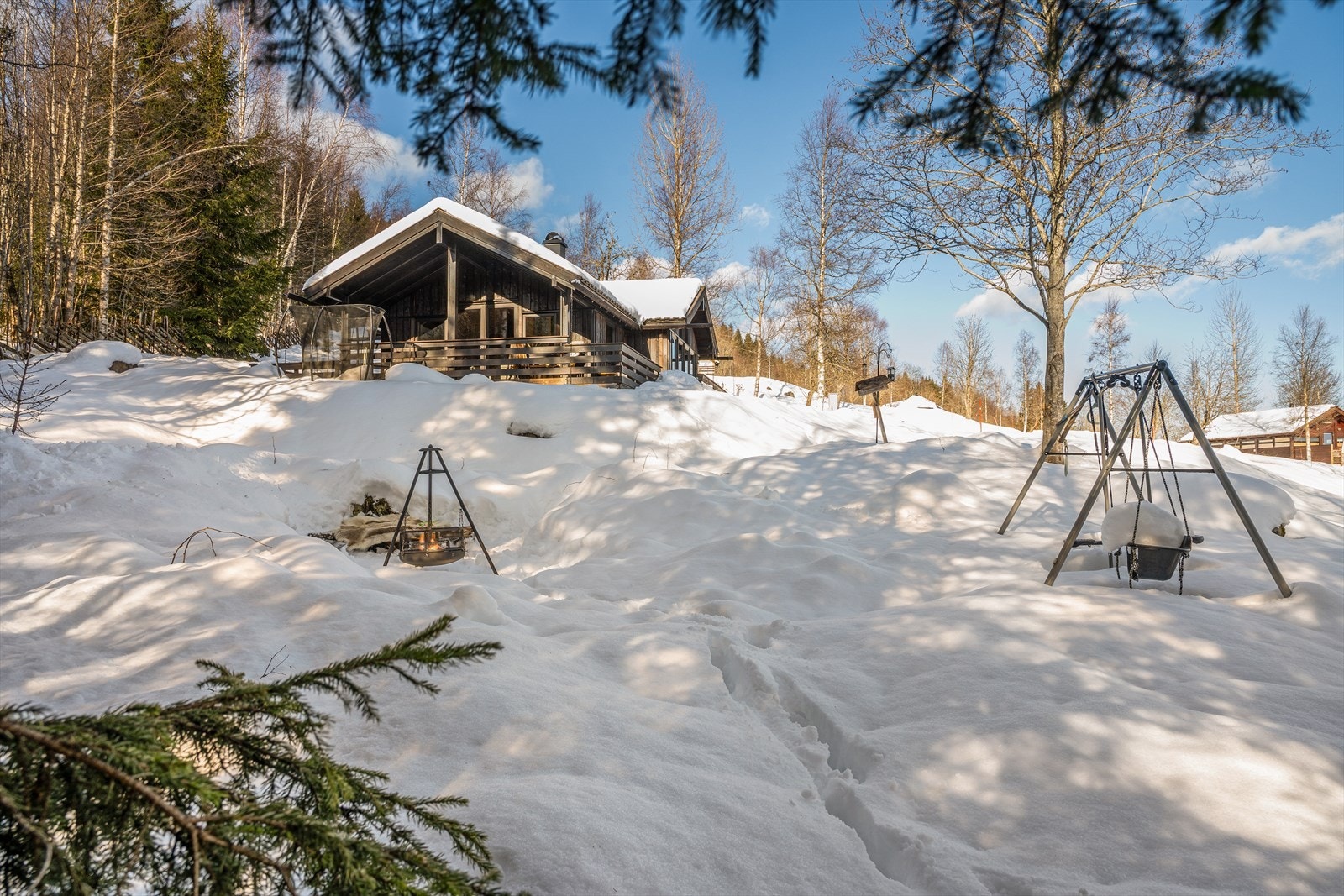 Nedenfor hytta er det laget en flott bålplass med sittebenker rundt bålpanna - perfekt for koselige kvelder med familie og venner under stjernehimmelen. For de minste, og de som bare er unge til sinns, medfølger også huskestativ og trampoline. Galleribilde