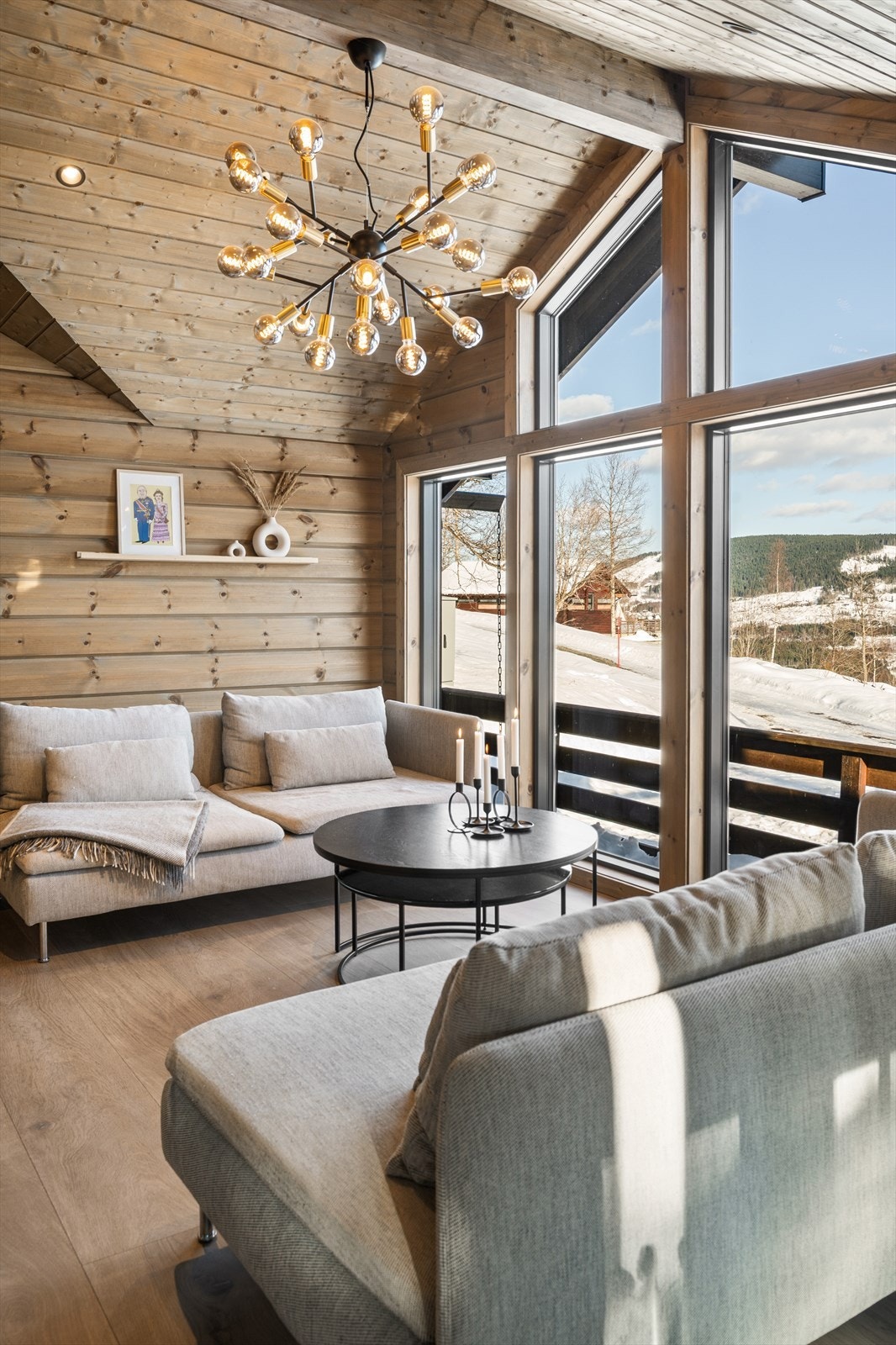 I taket er det integrert moderne downlightsspotter som gir et behagelig og jevnt lys, mens en elegant taklampe henger ned over sofabordet og blir et naturlig blikkfang i rommet. Galleribilde