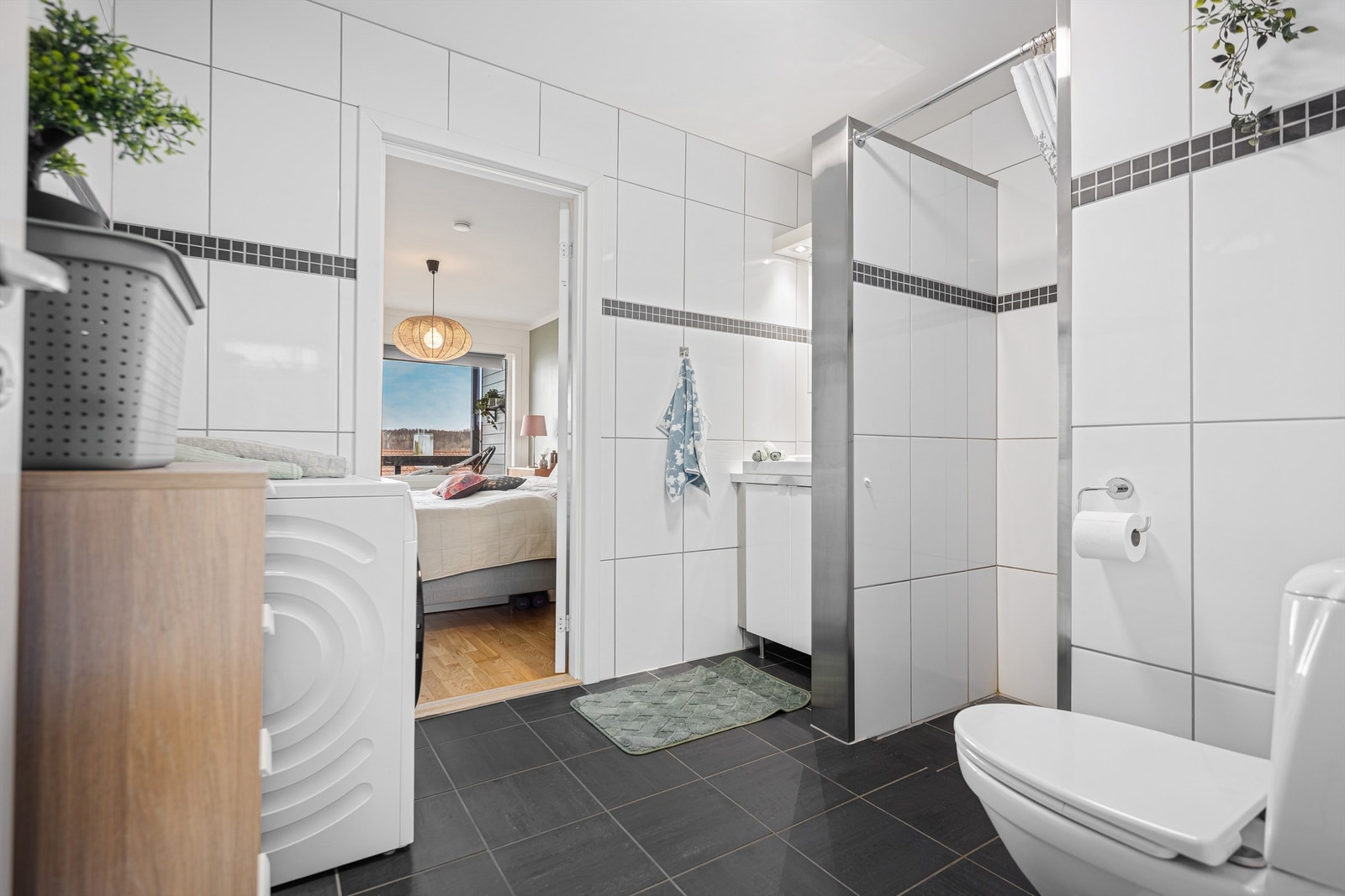 Helfliset bad av god størrelse og direkte tilgang til soverom. Det er varmekabler i gulv, servant og speilskap på vegg. Toalett, dusjnisje og opplegg for vaskemaskin. Galleribilde