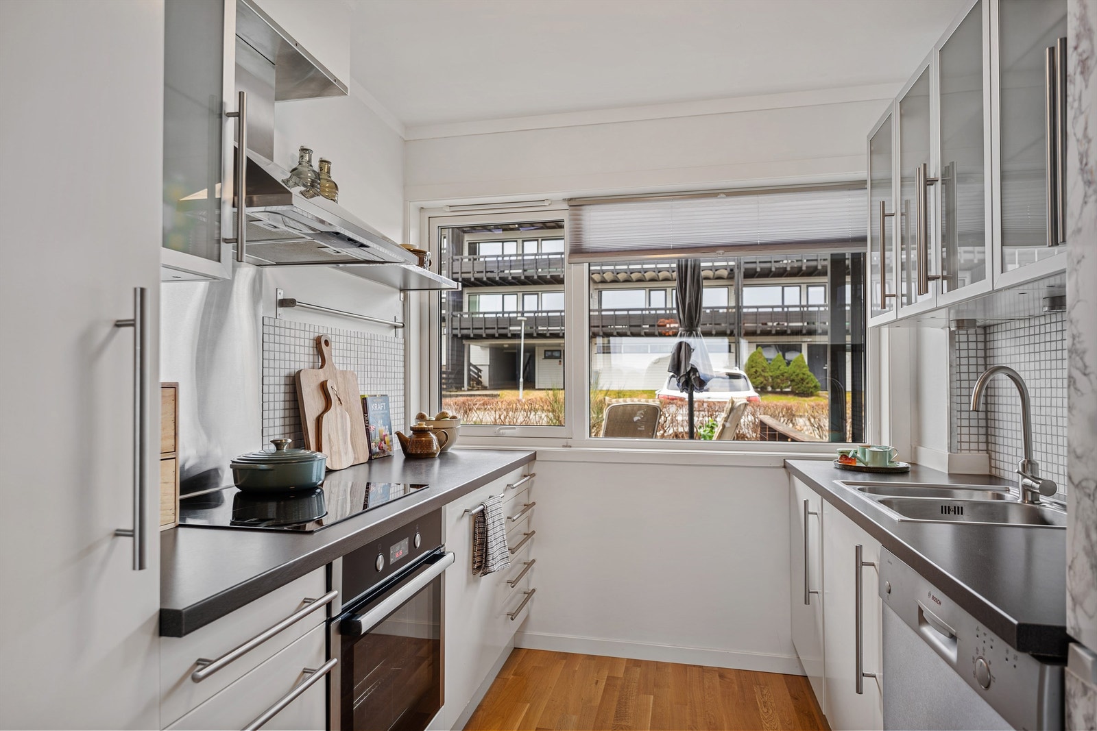 Kjøkkeninnredningen fra IKEA i tidløs hvit og grå benkeplate. Fliser på vegg mellom overskap og benk, i tillegg til stort vindu på endevegg, som gir godt lysinnslipp og utsikt mot inngangsparti og den sør-vendte terrassen. Galleribilde