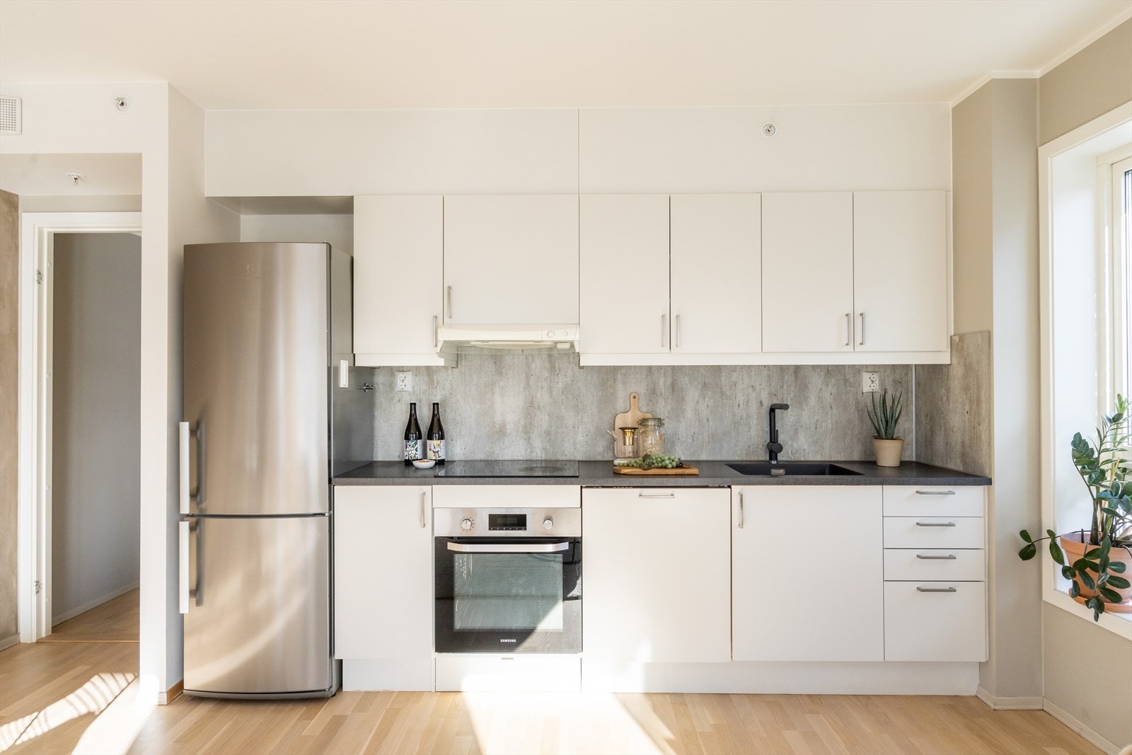 Kjøkkenet har et moderne preg og består av hvite, glatte fronter og benkeplate av laminat med planlimt vaskekum. Godt med benk- og skapplass! Galleribilde