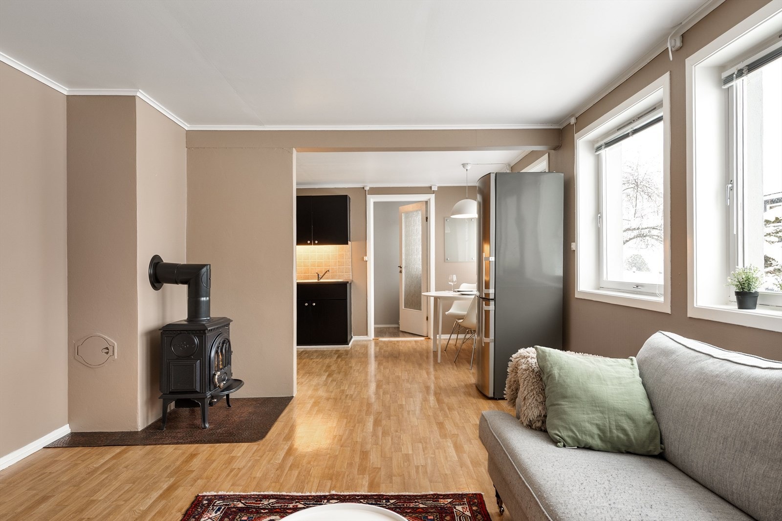 Stue med dels åpen løsning til kjøkken. Det er også peisovn i underetasjen. Galleribilde