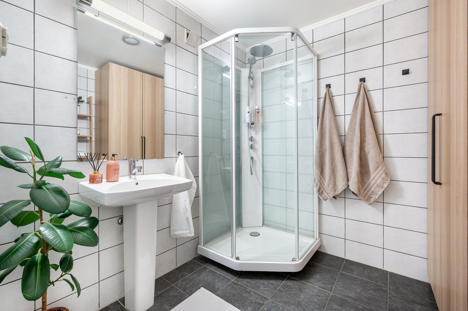 Lyst flislagt bad på ca. 5m² innredet med dusjkabinett og servant. Galleribilde