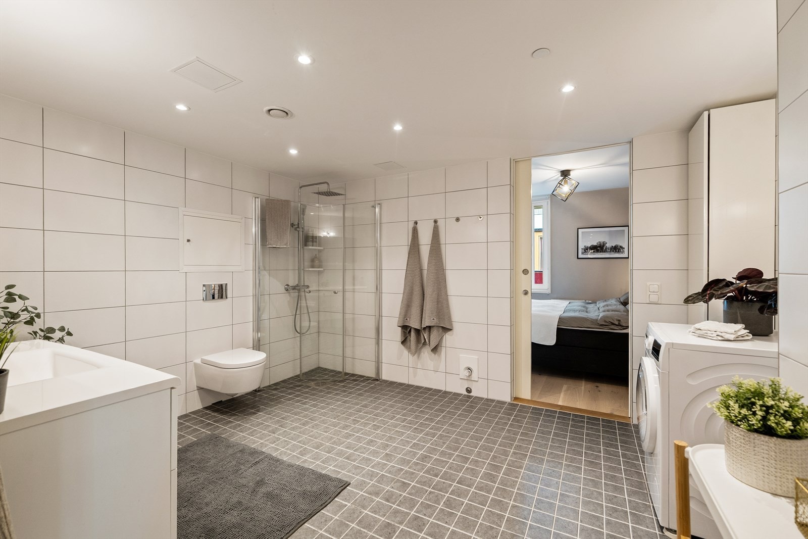 Rommet er innredet med baderomsinnredning, vegghengt toalett og dusjhjørne. Det er også mulighet til å sette inn badekar. Videre er det opplegg for både vaskemaskin og tørketrommel. Galleribilde