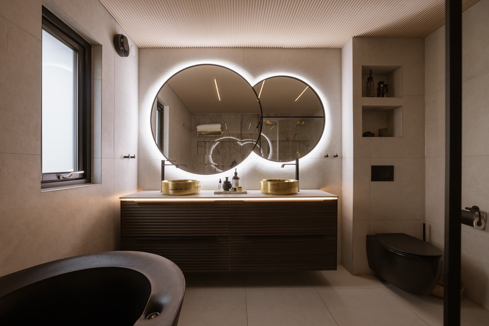 Badet har flislagte vegger og gulv samt malt himling, og er innredet med badekar, dobbel dusjnisje, dobbel servant med underskap og vegghengt toalett. Galleribilde