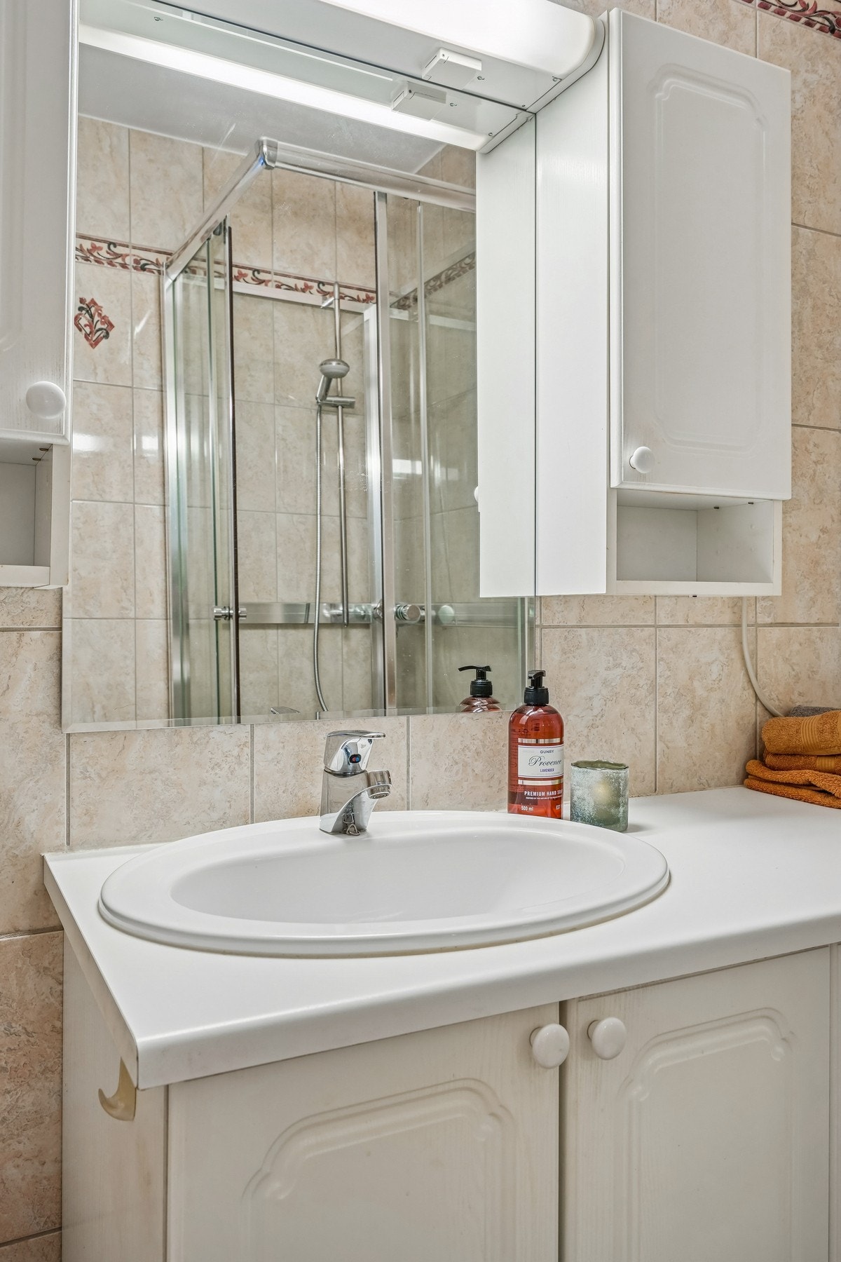 Innredning med profilerte skapfronter og benkeplate med nedfelt servant. Speil og belysning over. Galleribilde