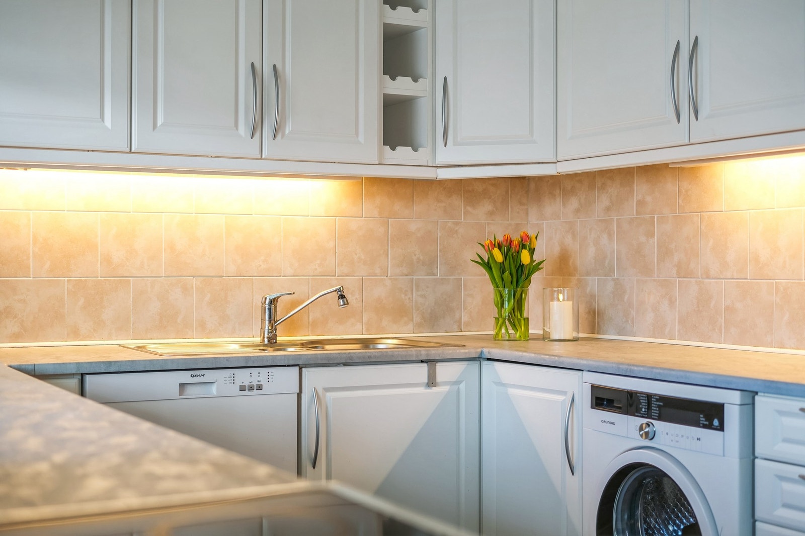 Det er montert fliser på veggen under overskap med belysning. Galleribilde