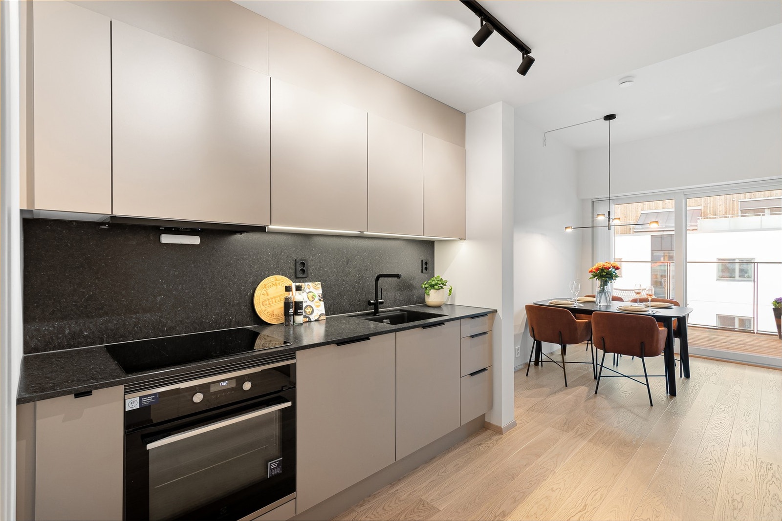 Kjøkkenet er velutstyrt og levert av HTH. Hvitevarer er integrerte og følger naturligvis med handelen. Sort spotskinne bidrar til god belysning i sonen, står i fin stil med det øvrige og medfølger også i handelen. Galleribilde