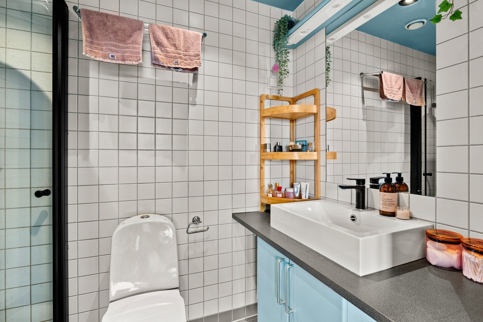 Flislagt og pent bad med dusjhjørne, vegghengt toalett og servant med underskap. Galleribilde