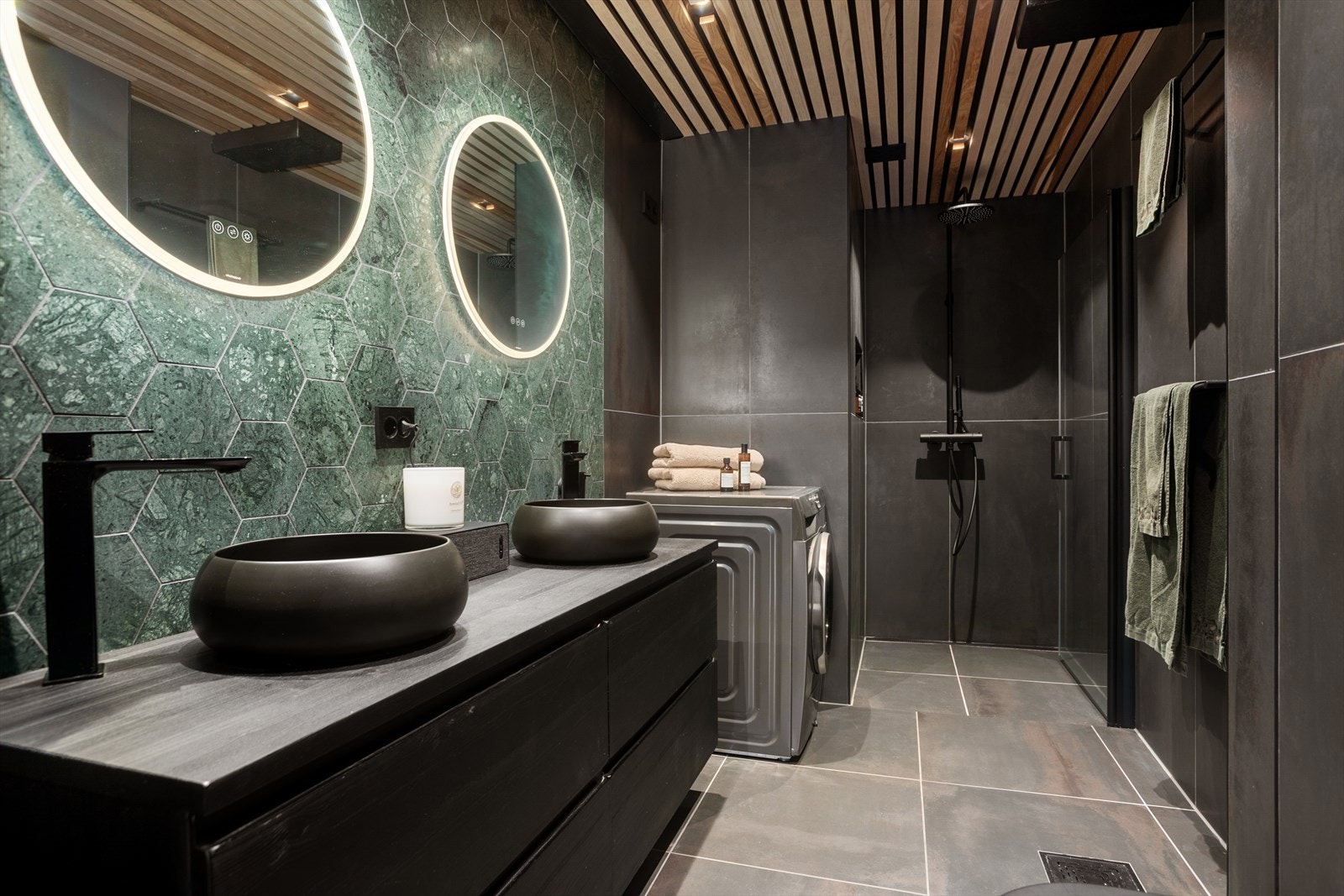 Eksklusivt bad fra 2021 med mørk fargepalett og innslag av varme spiler for et rolig uttrykk. Baderomsinnredning fra Vikingbad og armatur fra Tapwell. Galleribilde