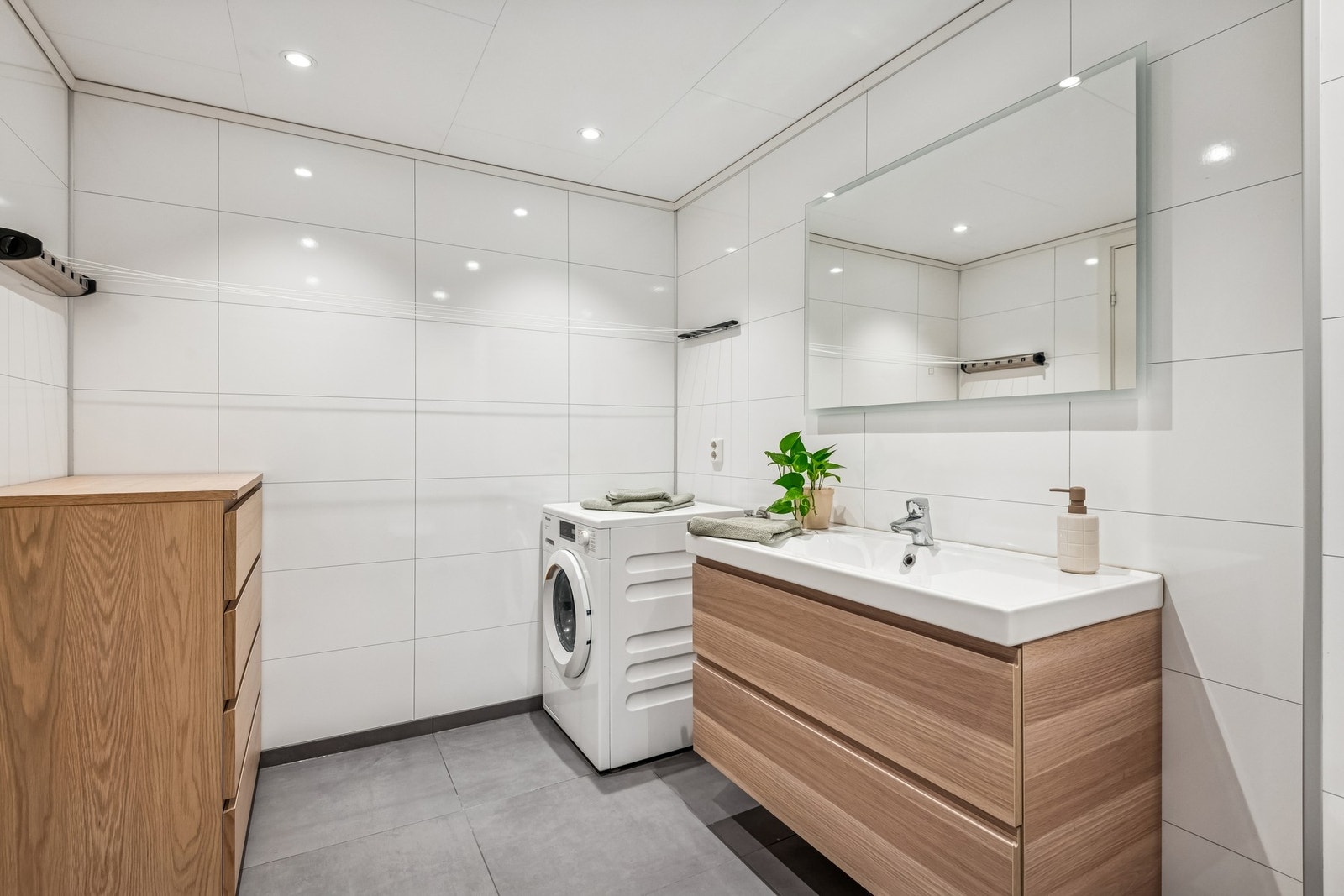 Badet er innredet med moderne innredning, dusjhjørne, toalett og opplegg for vaskemaskin. Galleribilde