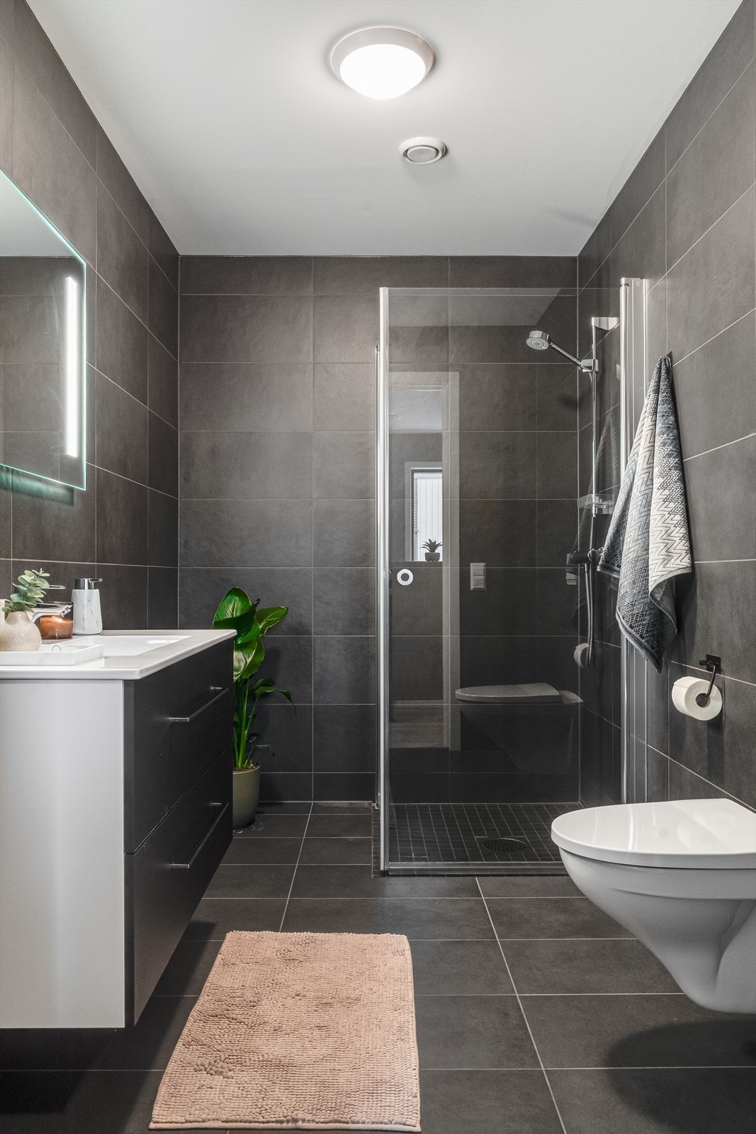 Begge bad er flislagt og har elektriske varmekabler i gulvet, innredning med nedfelt servant, veggmontert toalett og dusjvegger/hjørne Galleribilde