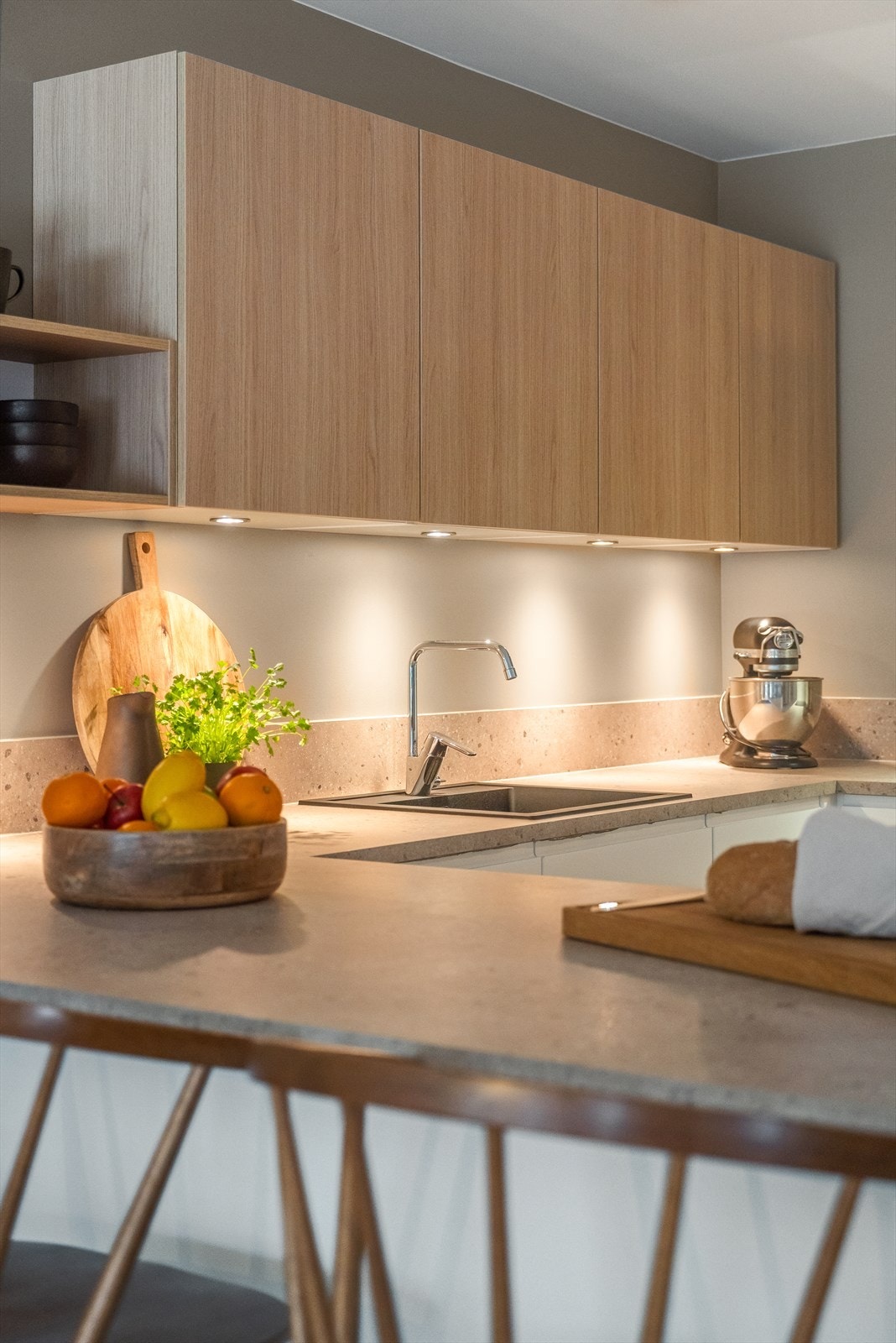 Tiltalende forlenget benkeplate mellom overskap for enklere renhold og godt med belysning Galleribilde