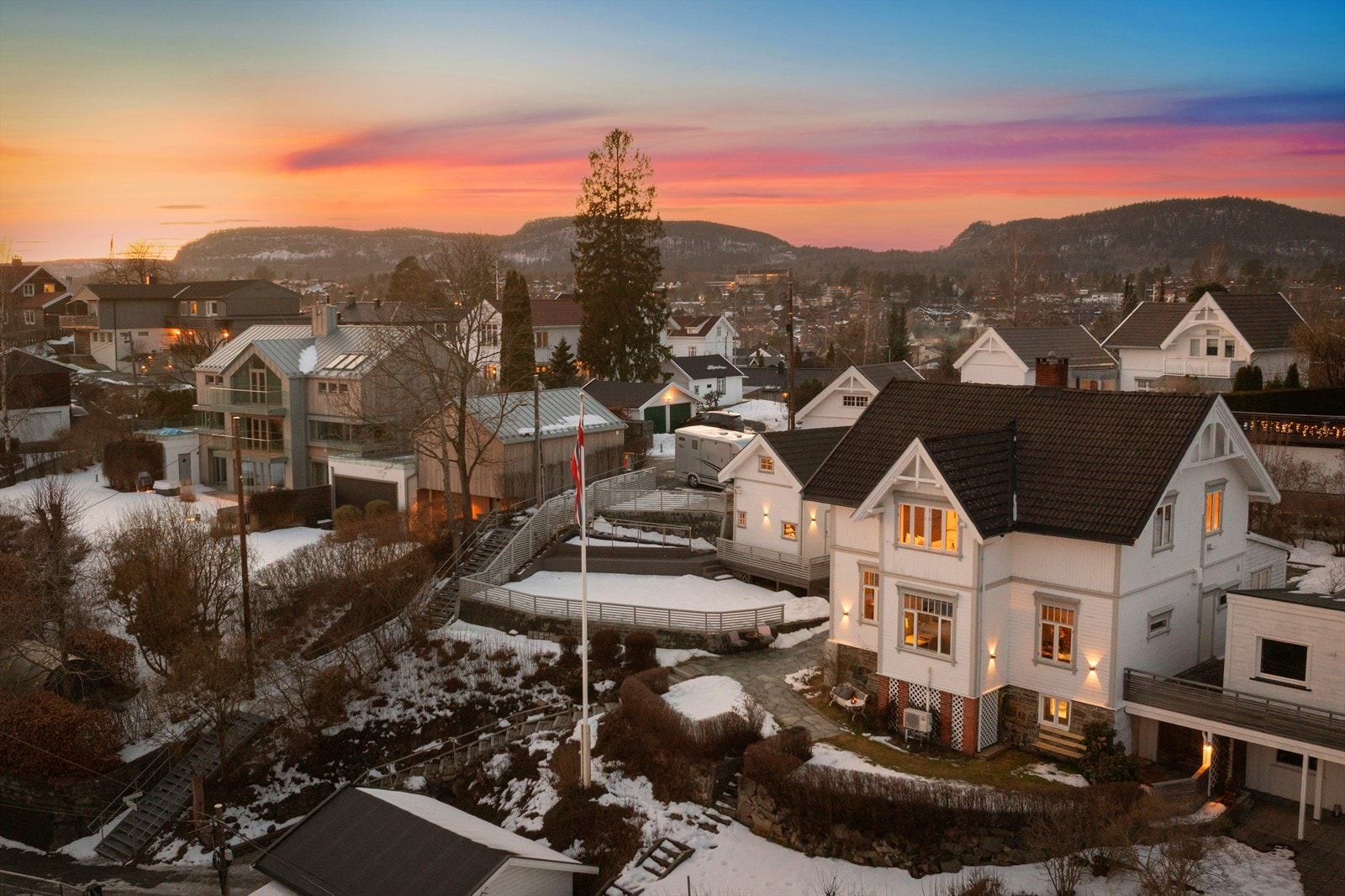 Den terrasserte tomten er opparbeidet med steinsatt gårdsplass og dobbelgarasje i sørvest, og en flott terrengtrapp fører oss til neste nivå med hellelagte stier, skjermet markterrasse og stor gressplen nord, syd og vest Galleribilde