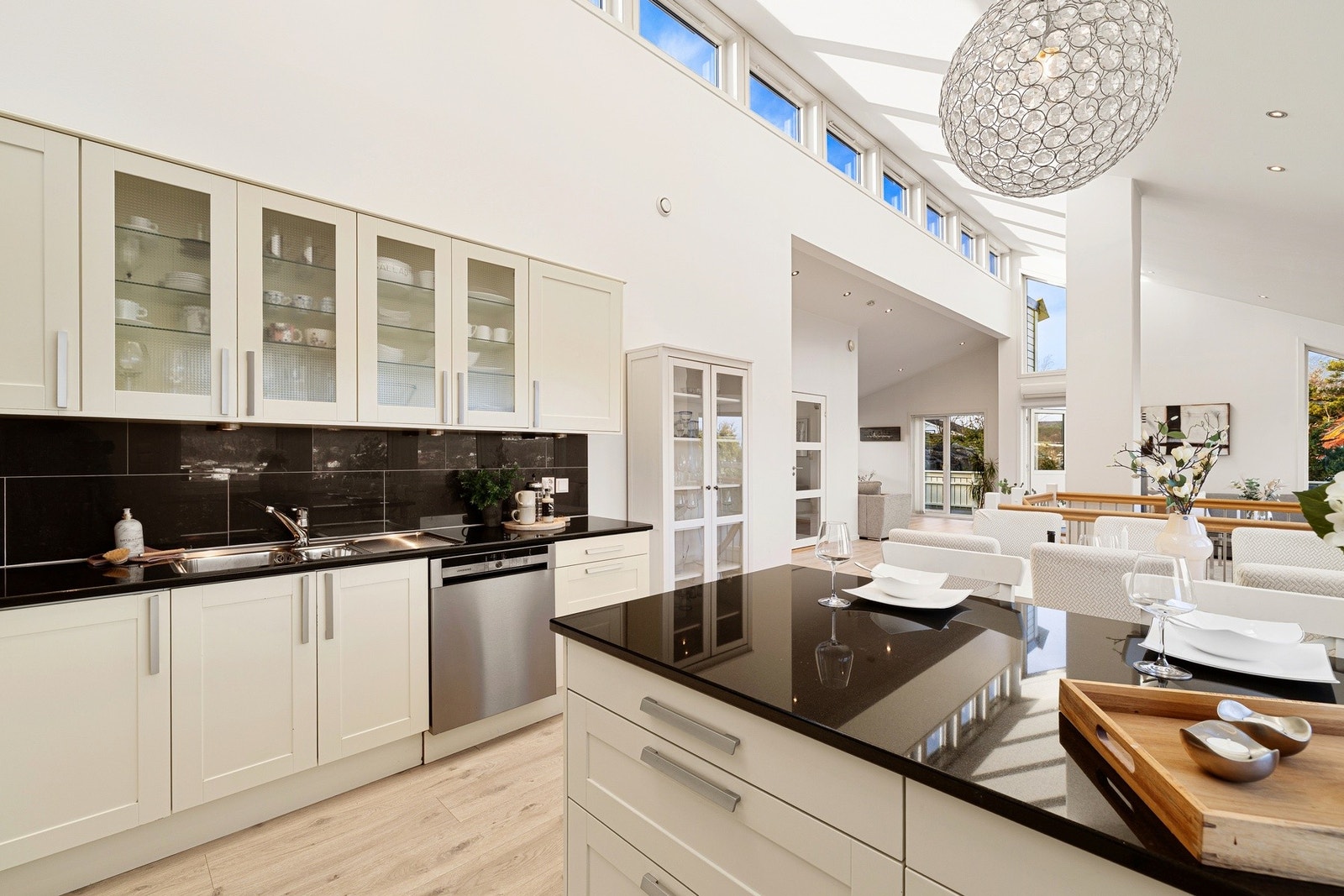 Stort og luftig kjøkken med spiseplass ved kjøkkenøyen som rammer inn kjøkkensonen Galleribilde