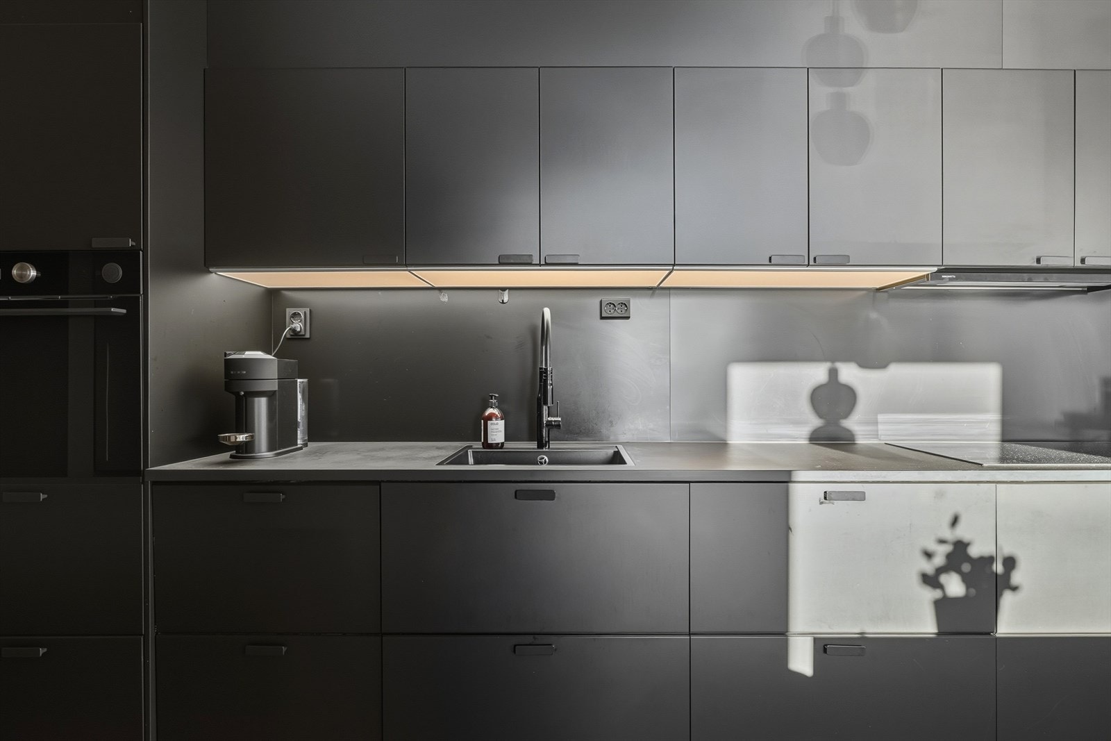 Kjøkkeninnredningen har en sømløs visuell utførelse, med integrerte hvitevarer, samt benkeplate og bakvegg som går ton i ton med innredningen. Galleribilde