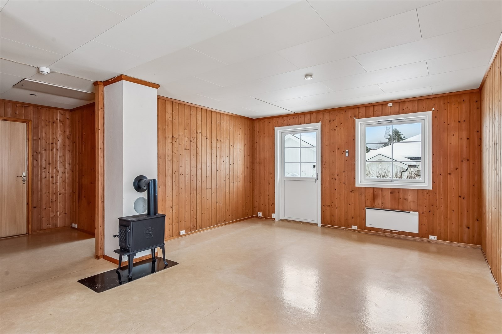 Oppholdsrommet har vinylbelegg på gulvet og panel på veggene. Galleribilde