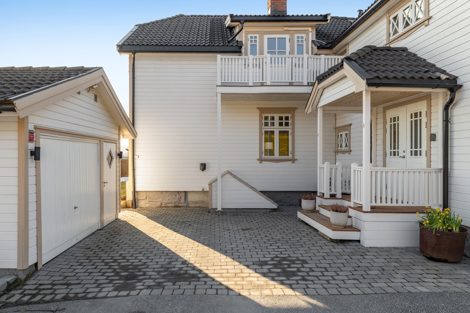 Et innbydende inngangsparti og en gårdsplass belagt med betongstein ønsker velkommen til boligen. Galleribilde