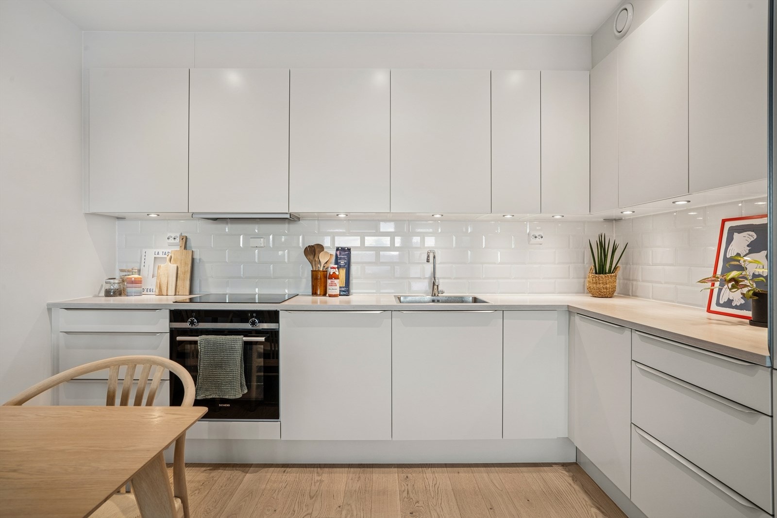 Kjøkkenet har en hvit innredning med moderne glatte fronter og laminat benkeplate. Galleribilde