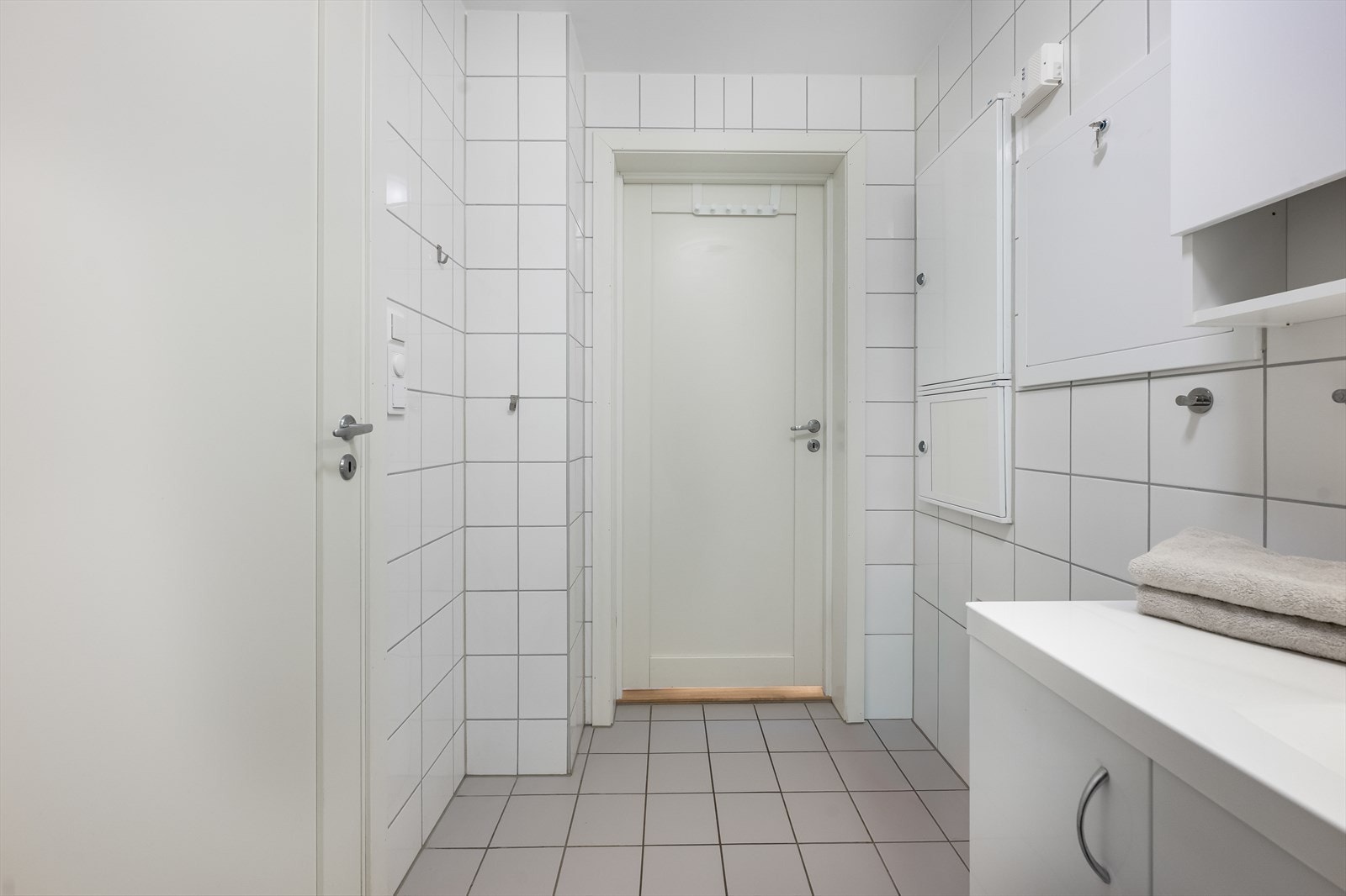 Rommet har flislagte overflater, varmekabler i gulvet og en dør videre inn til bad/vaskerommet. Galleribilde