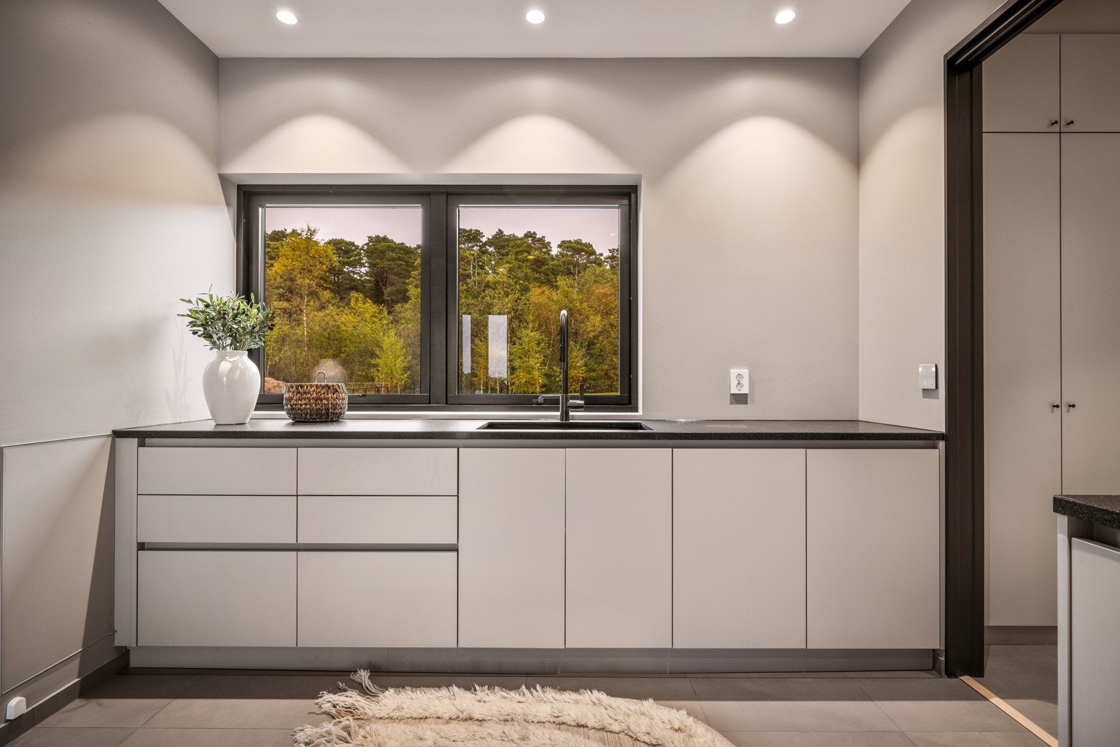 - Videre har man en sort, matt benkeplate av granitt med underlimt vask, dornbrachk armatur og flislagt gulv - Galleribilde