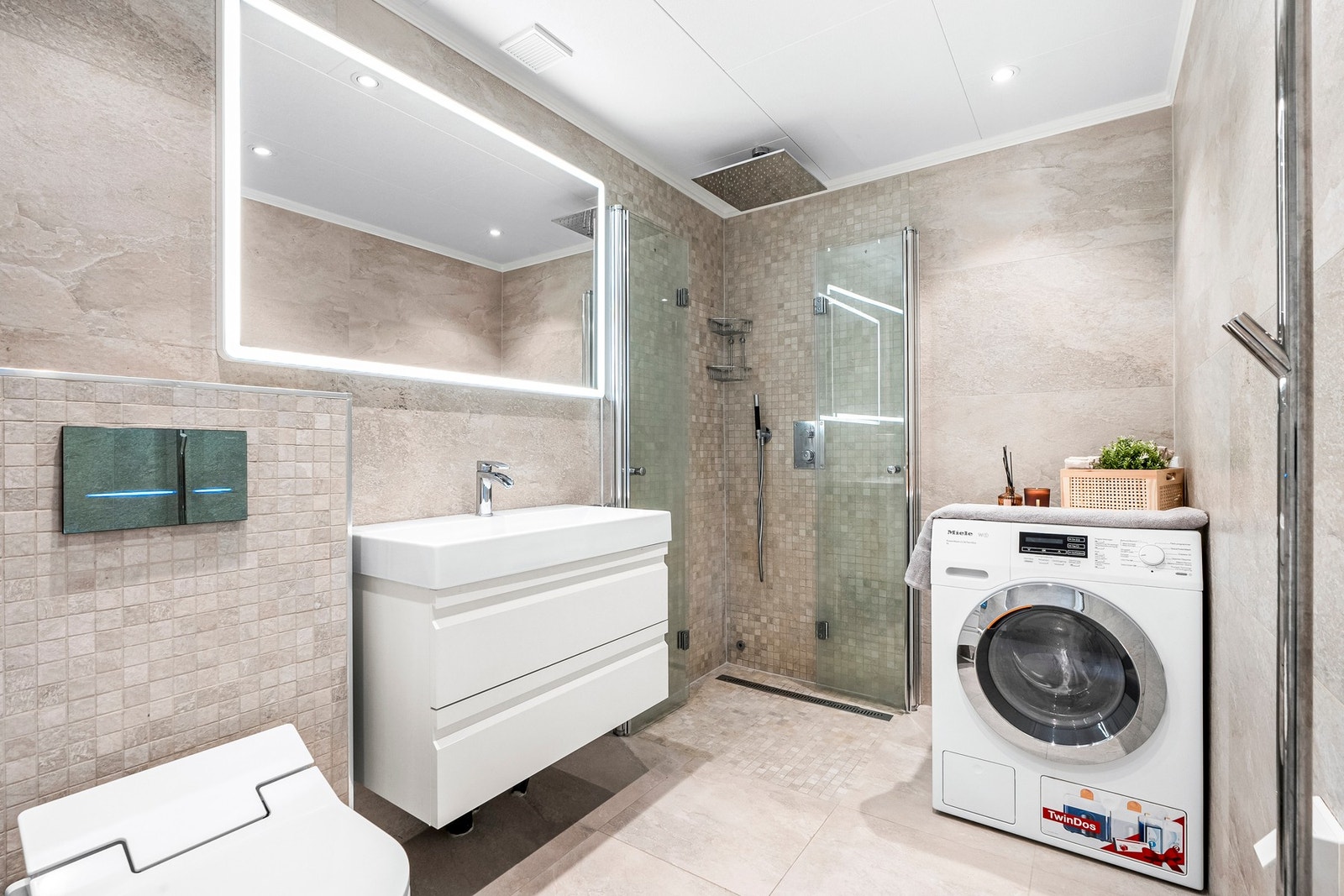 Pent flislagt bad/wc fra 2018 med takdusj, speil med integrert belysning, berøringsfri betjeningsplate og opplegg for vaskemaskin. Galleribilde