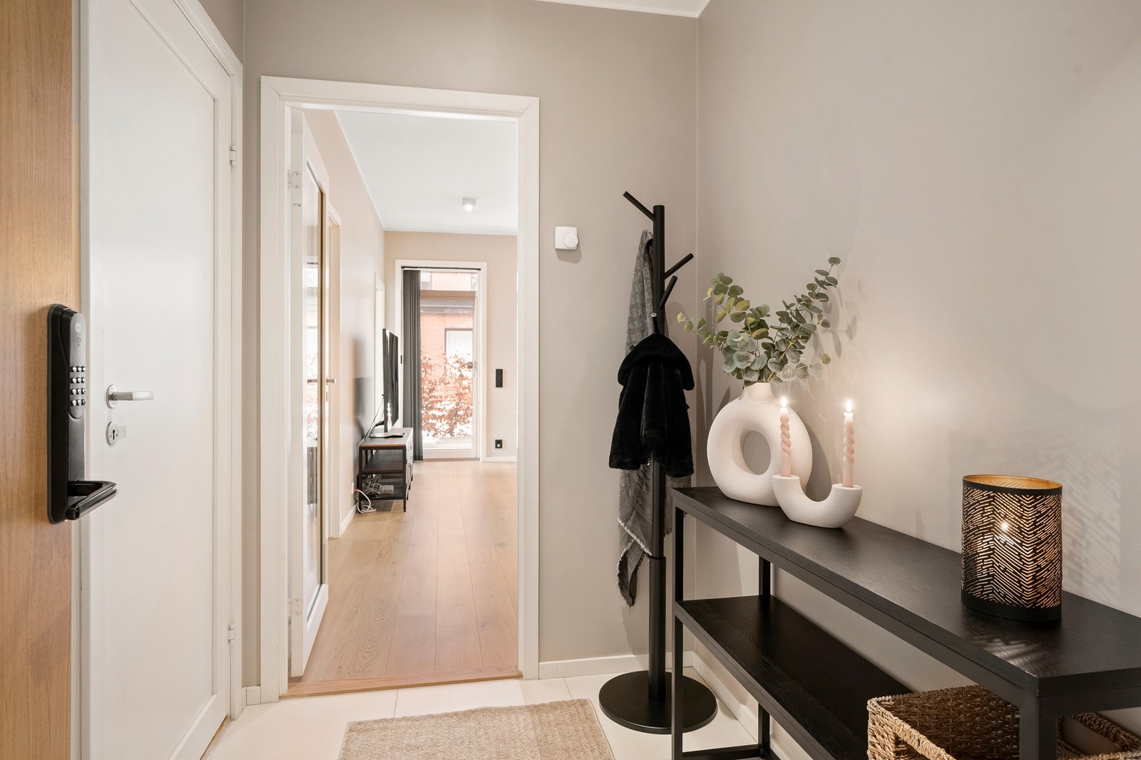 Innbydende entré som gir et godt førsteinntrykk. Her er det malte vegger i en varm sandfarge og store, lyse gulvfliser over vannbåren gulvvarme. Galleribilde