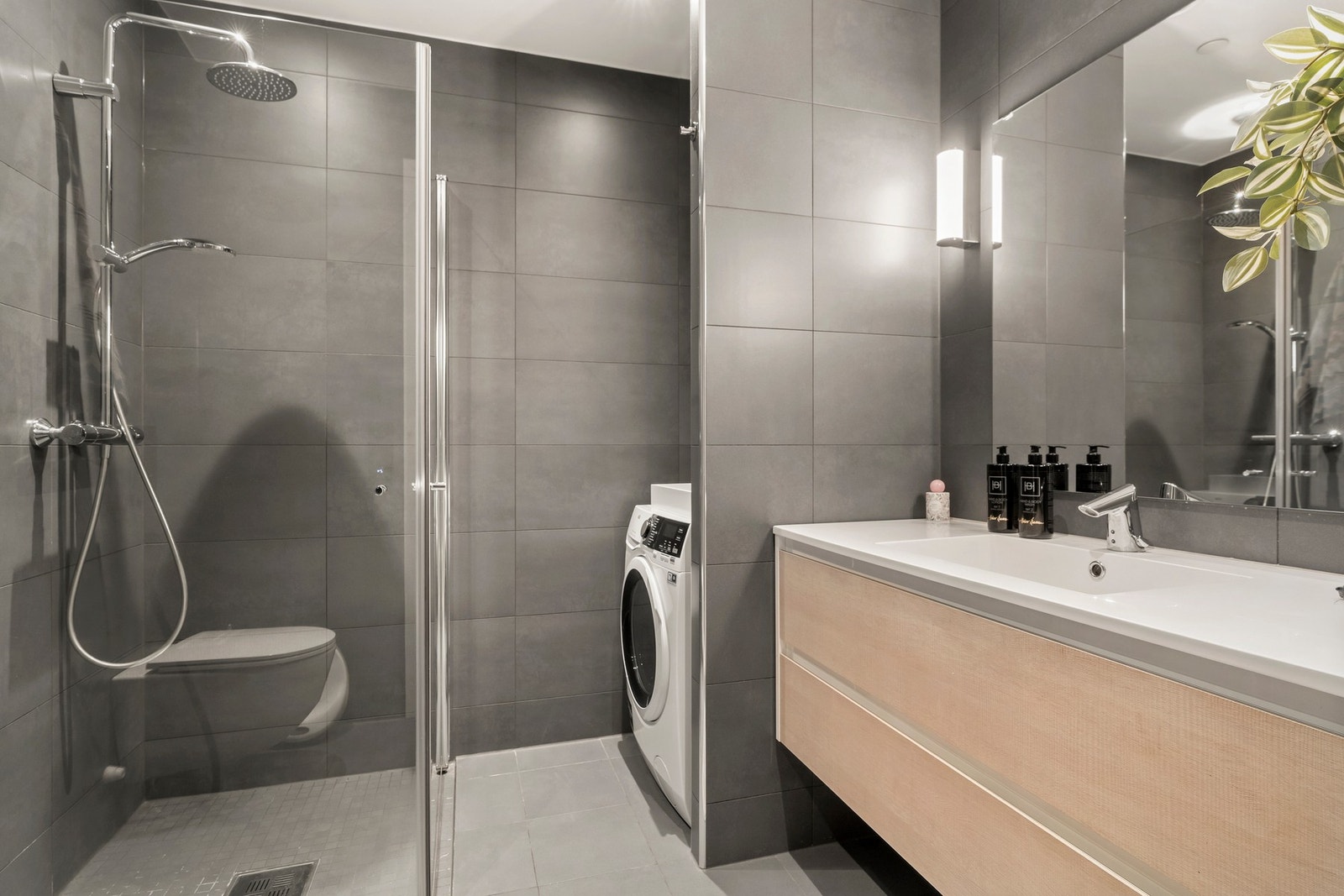 Baderommet er smakfullt innredet med store, matte veggfliser i dempet sort og lysegrå gulvfliser med varmekabler. Galleribilde