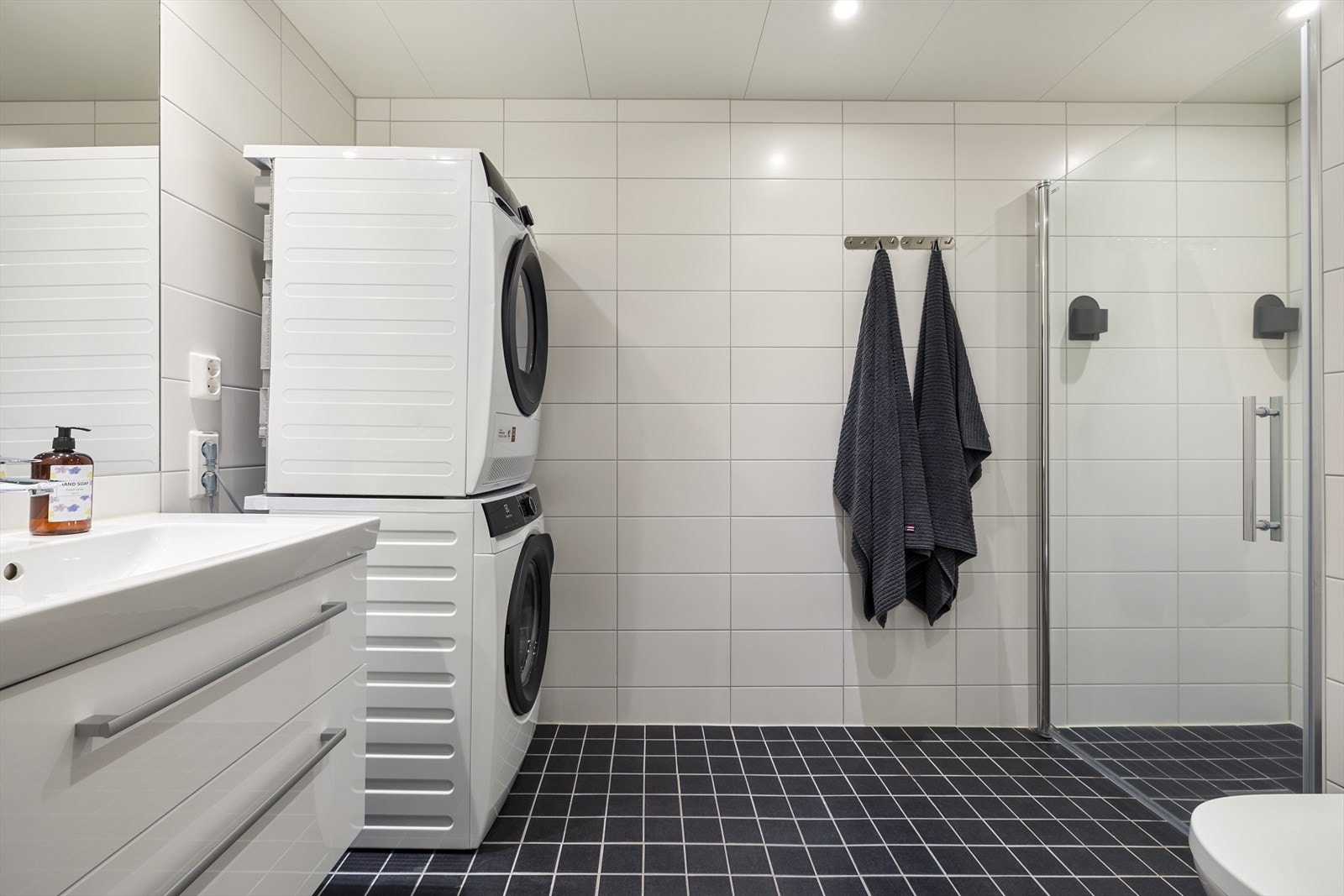 Badet i leiligheten har flislagte vegger og gulv og himlingsplater. Galleribilde