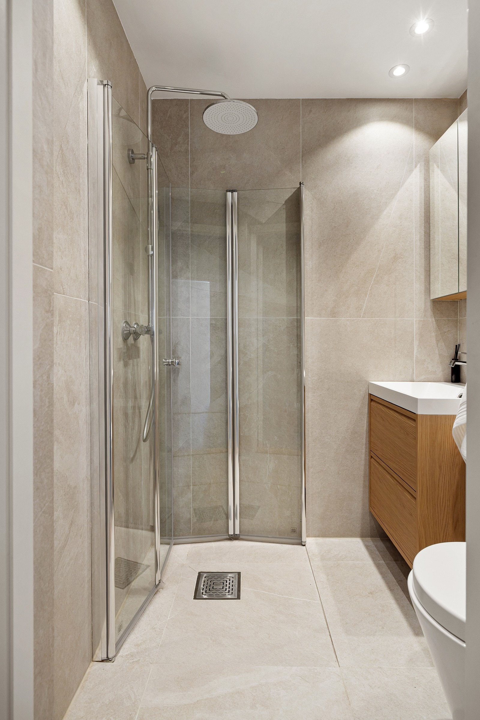 Baderommet er også utstyrt med dusjhjørne med innfellbare glassdører og både hånd- og regnfallsdusj, samt vegghengt toalett. Galleribilde