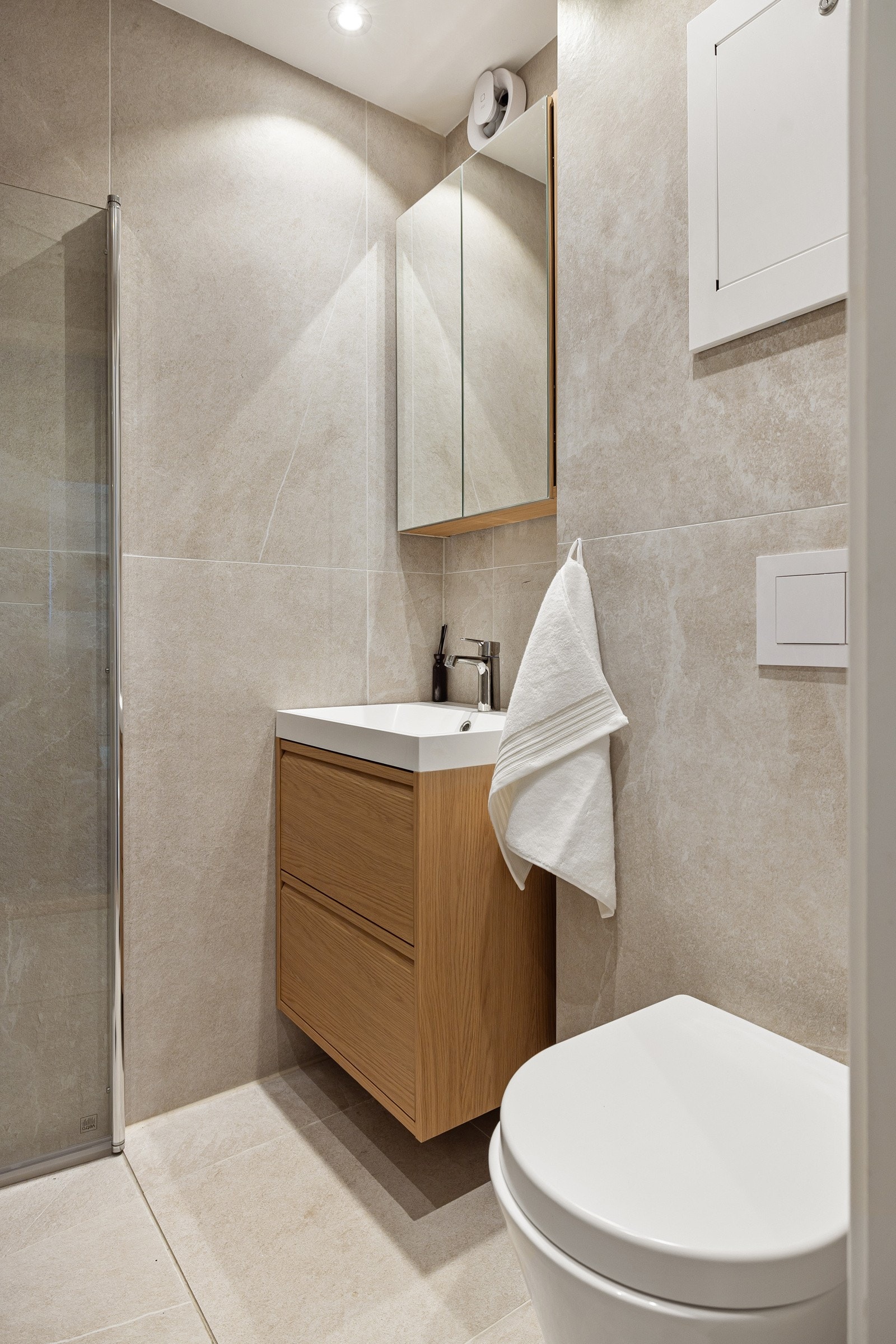 Pen baderomsinnredning med skuffer og heldekkende servant, vegghengt speilskap over. Galleribilde